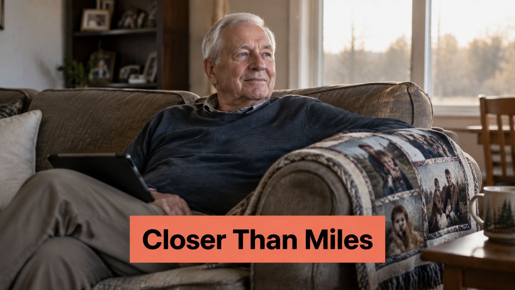 An elderly man smiling while holding a personalized photo blanket featuring family portraits on his couch.