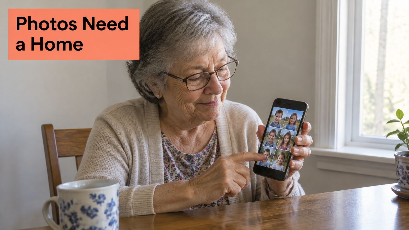 An elderly woman smiling while pointing at a mobile phone screen displaying photos of young children.