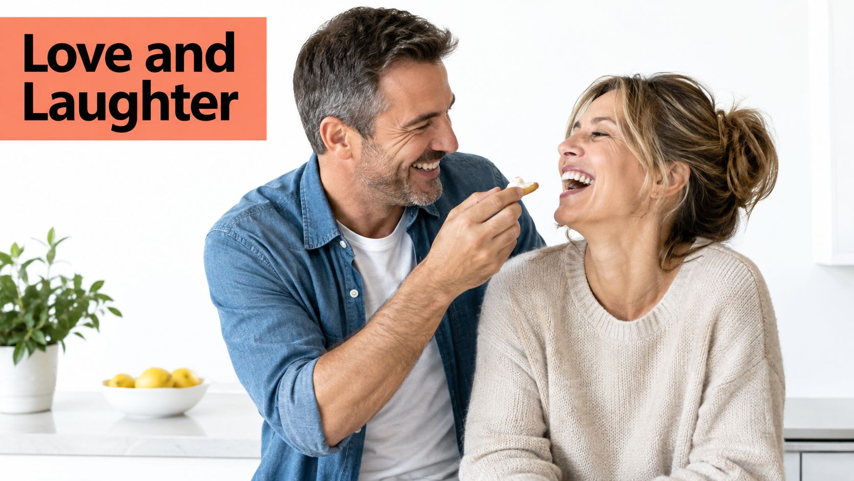 A happy middle aged couple laughing while sharing a snack in a bright home kitchen