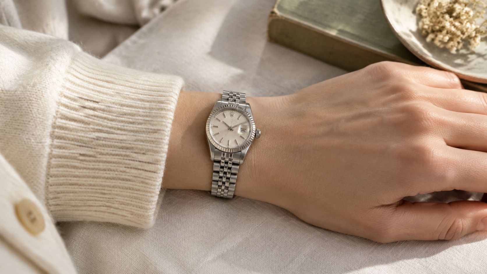 A elegant woman's wrist wearing a vintage silver Rolex 6917 watch with a fluted bezel and jubilee bracelet.