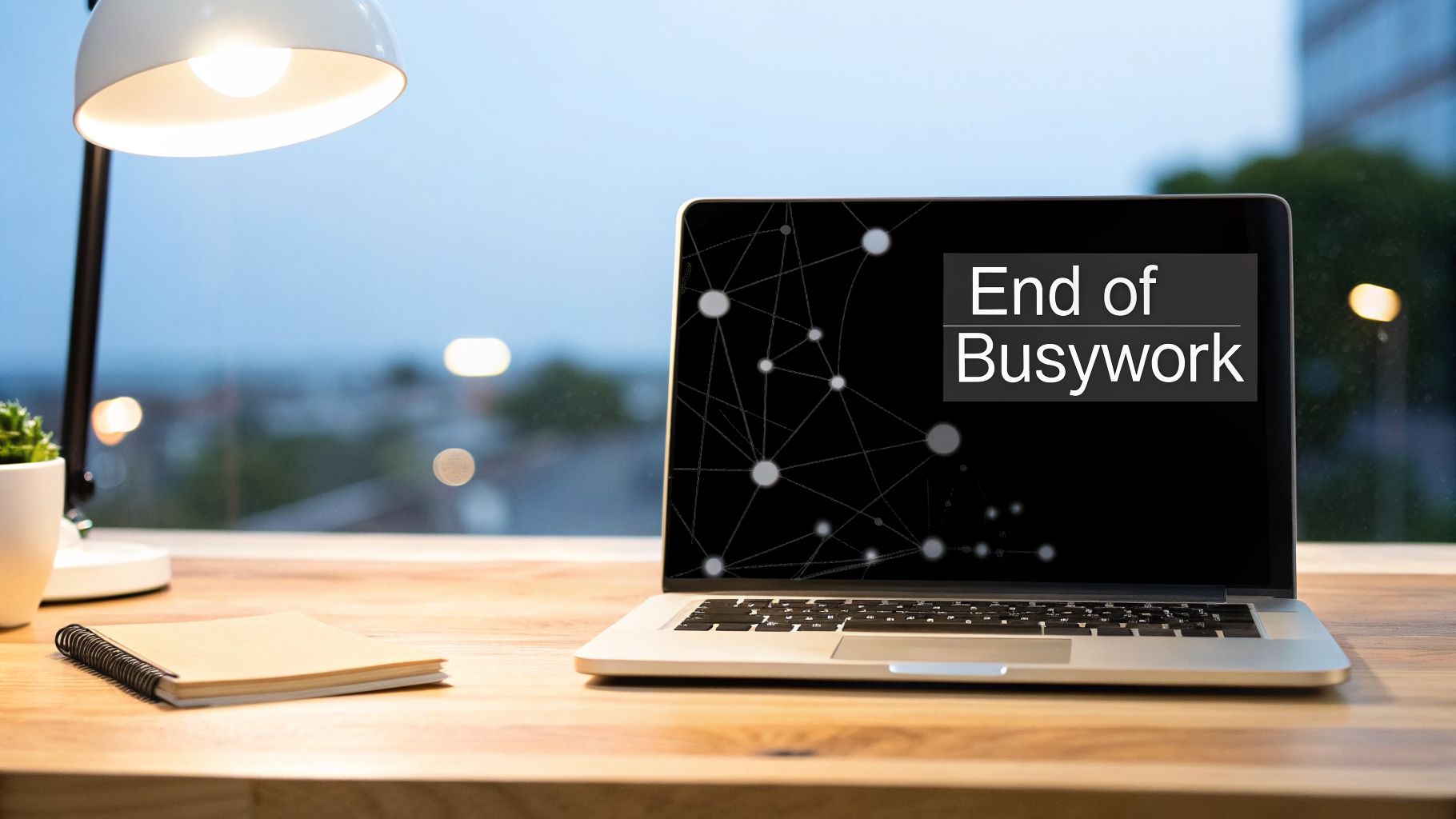 Laptop on a wooden desk displaying 'End of Busywork', next to a lamp, plant, and notebook.