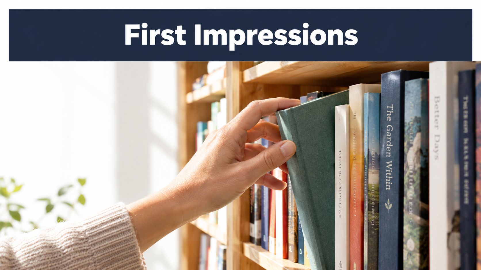 A close-up view of a person's hand reaching to pick a green book from a wooden bookshelf.