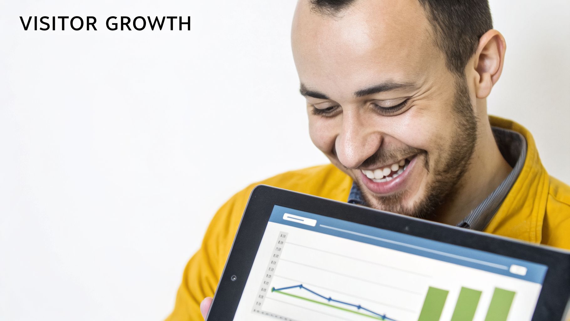 A happy man smiles while looking at visitor growth charts displayed on a tablet.