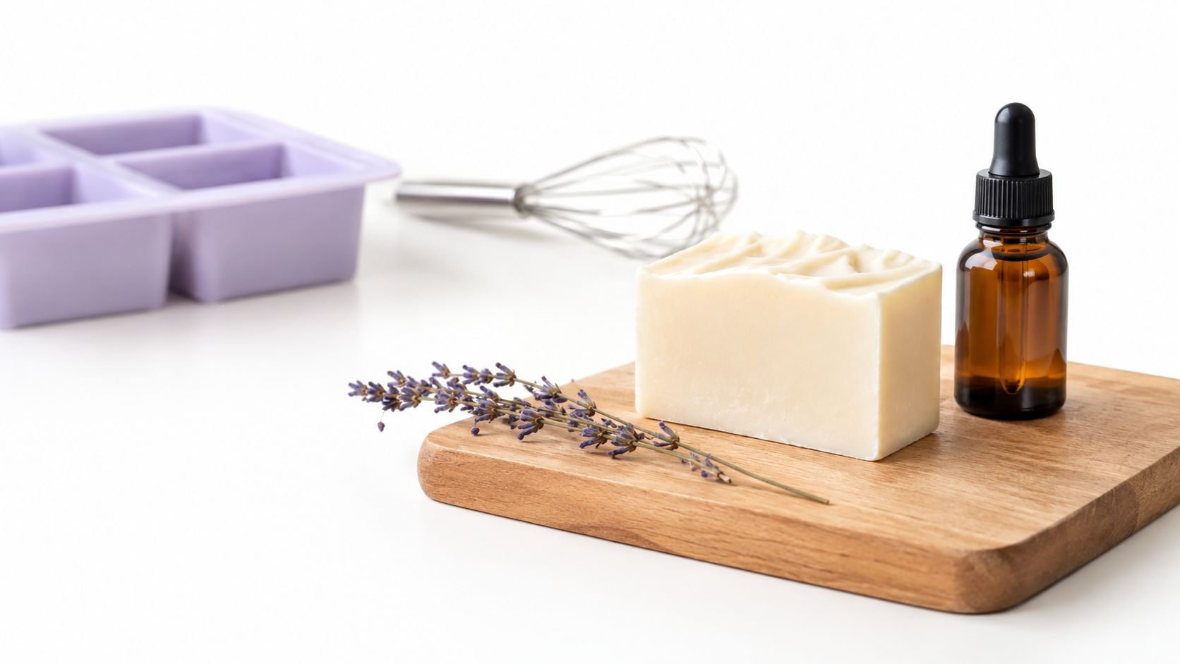 A bar of soap, a sprig of dried lavender, and a dropper bottle on a wooden board.