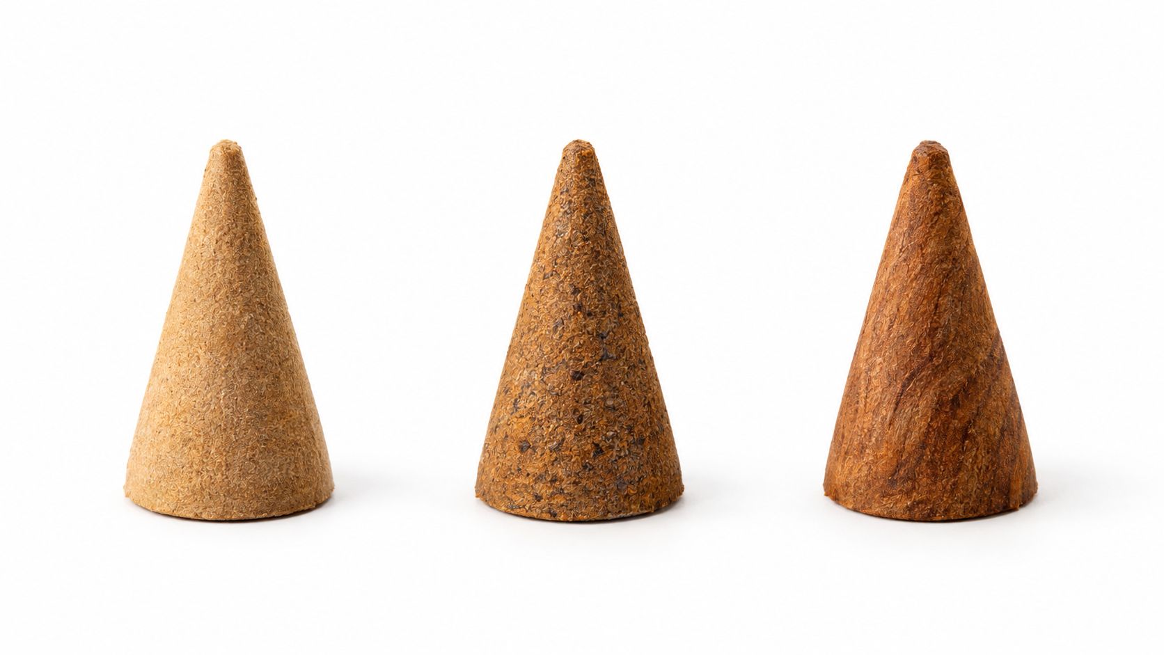 Three different textured incense cones standing upright on a clean white background