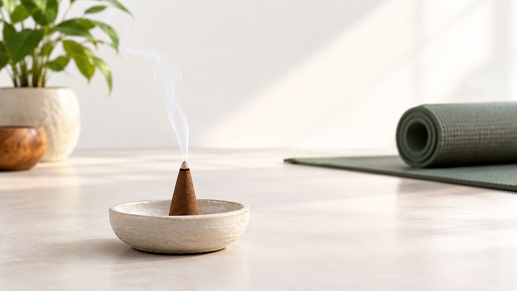 A burning sandalwood incense cone sits in a ceramic dish with smoke rising against a minimalist background.