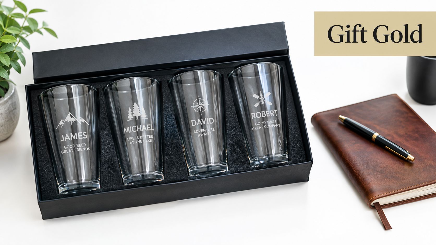 A set of four personalized pint beer glasses with engraved names and designs displayed in a black gift box.