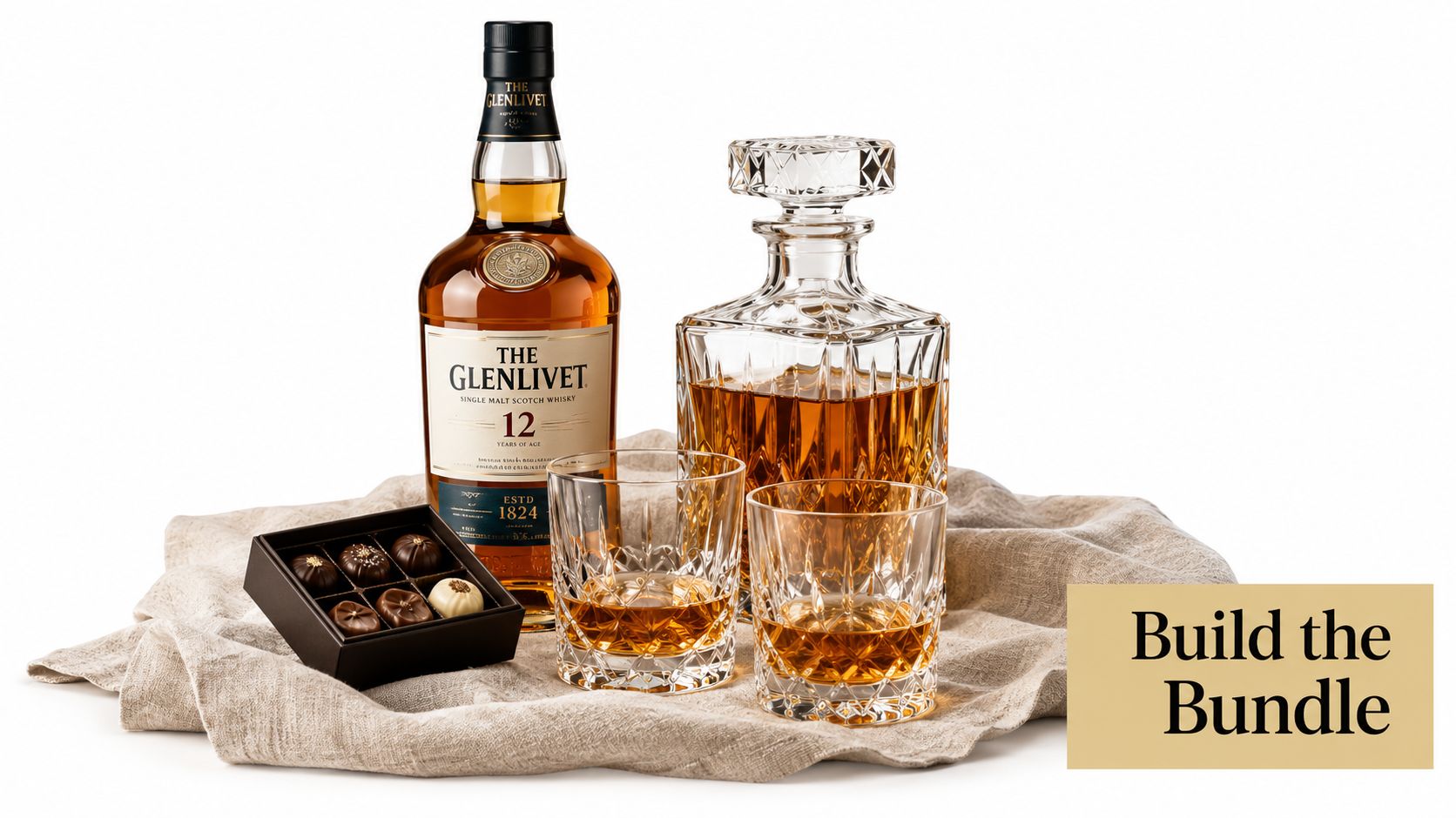A luxurious whisky gift set featuring a bottle of The Glenlivet 12, a crystal decanter, glasses, and chocolates.