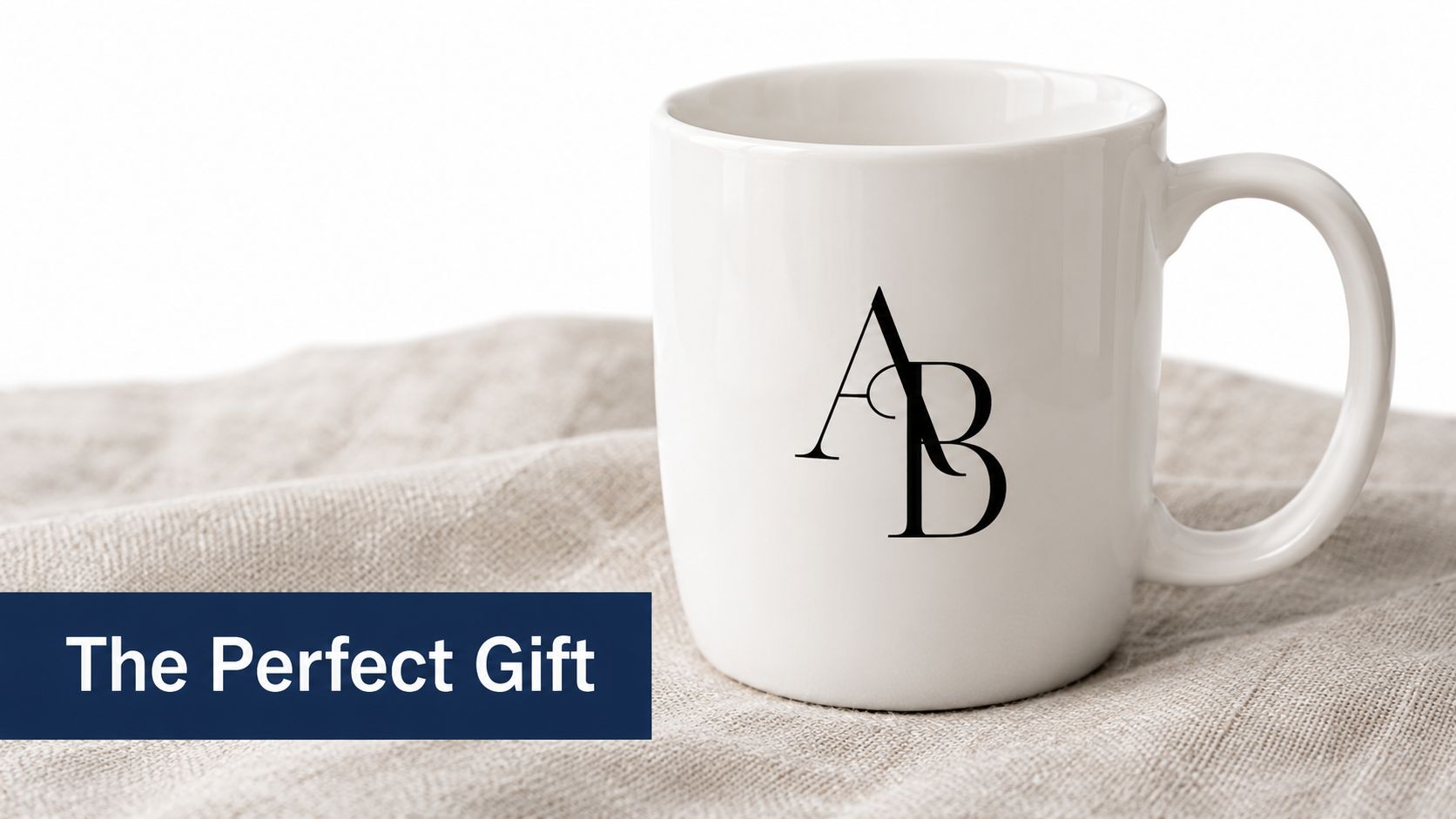 A minimalist white ceramic coffee mug featuring an elegant black AB monogram logo, resting on a textured fabric.