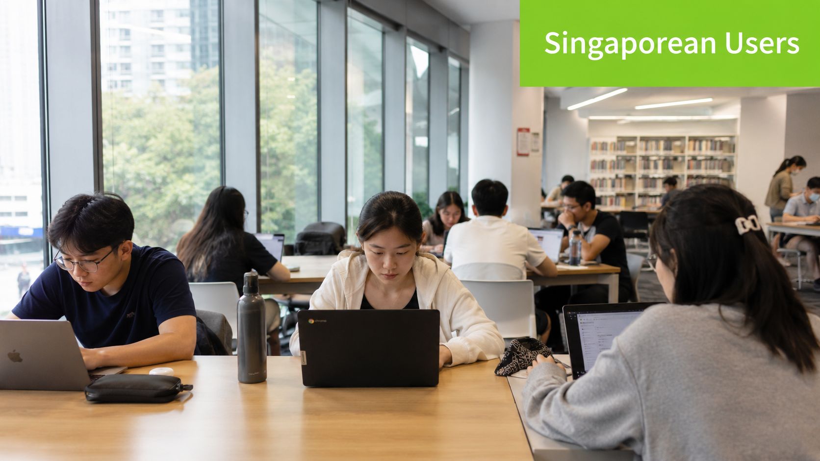 A group of university students working on their laptops at a quiet shared study space.