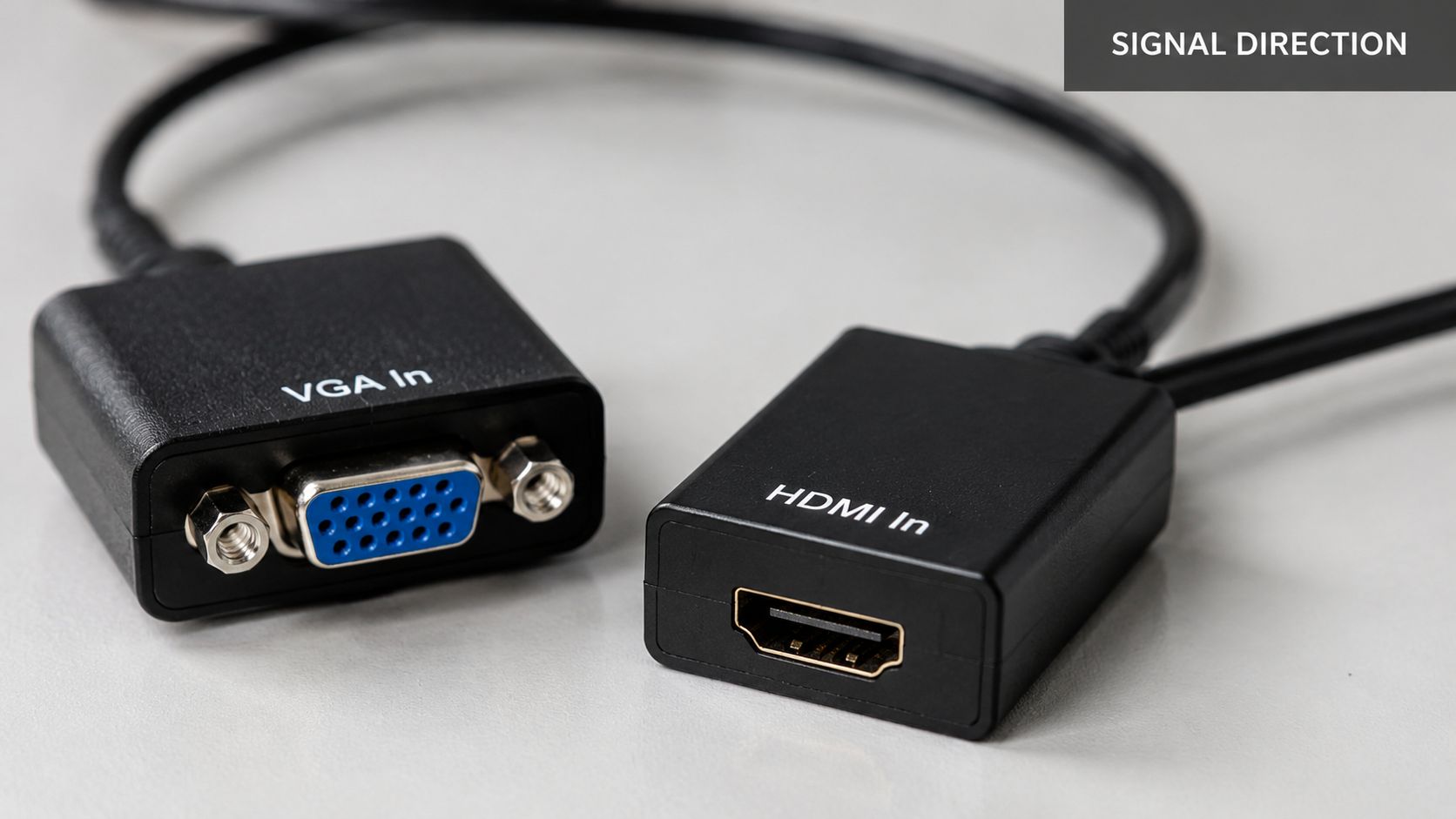 A black video adapter cable featuring a VGA input connector and an HDMI input connector on a table.