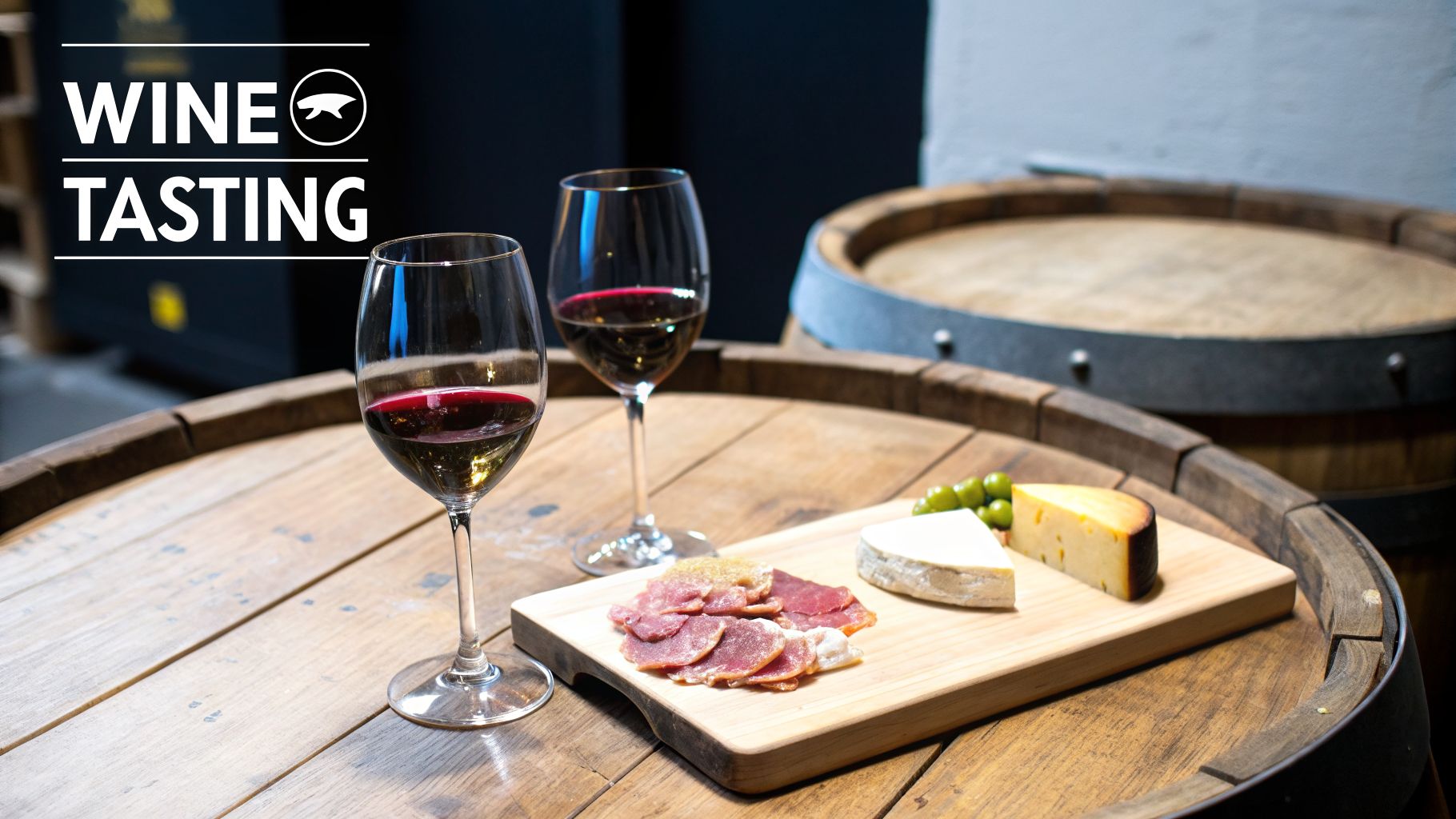 Two glasses of red wine, charcuterie, cheese, and olives on a wooden wine barrel.