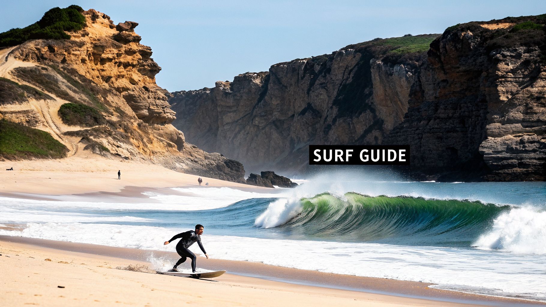 A surfer in a wetsuit rides a vibrant green wave on a sandy beach next to majestic cliffs.