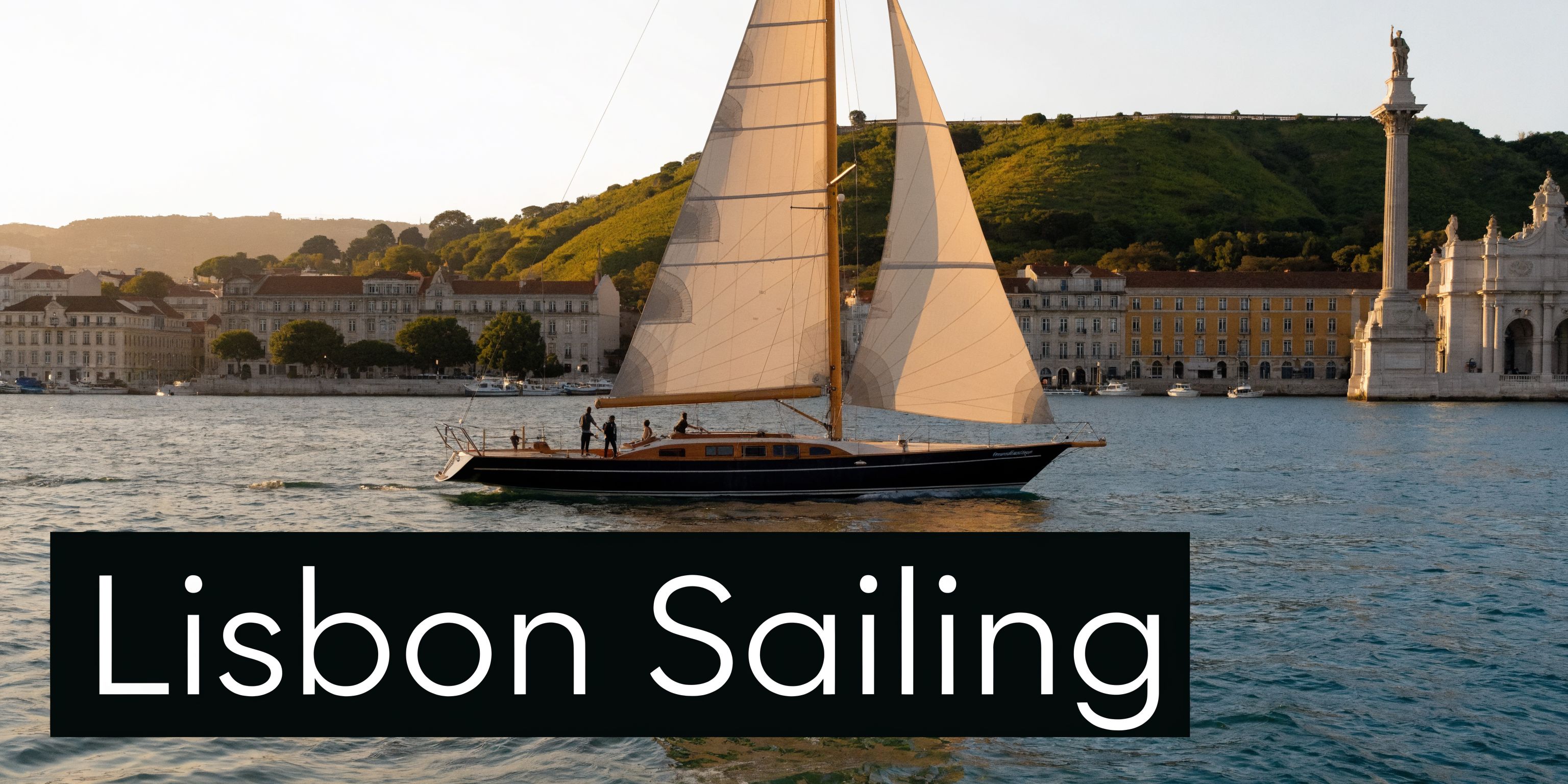 A classic wooden sailboat cruising on the Tagus River in front of the historic Lisbon cityscape in Portugal.