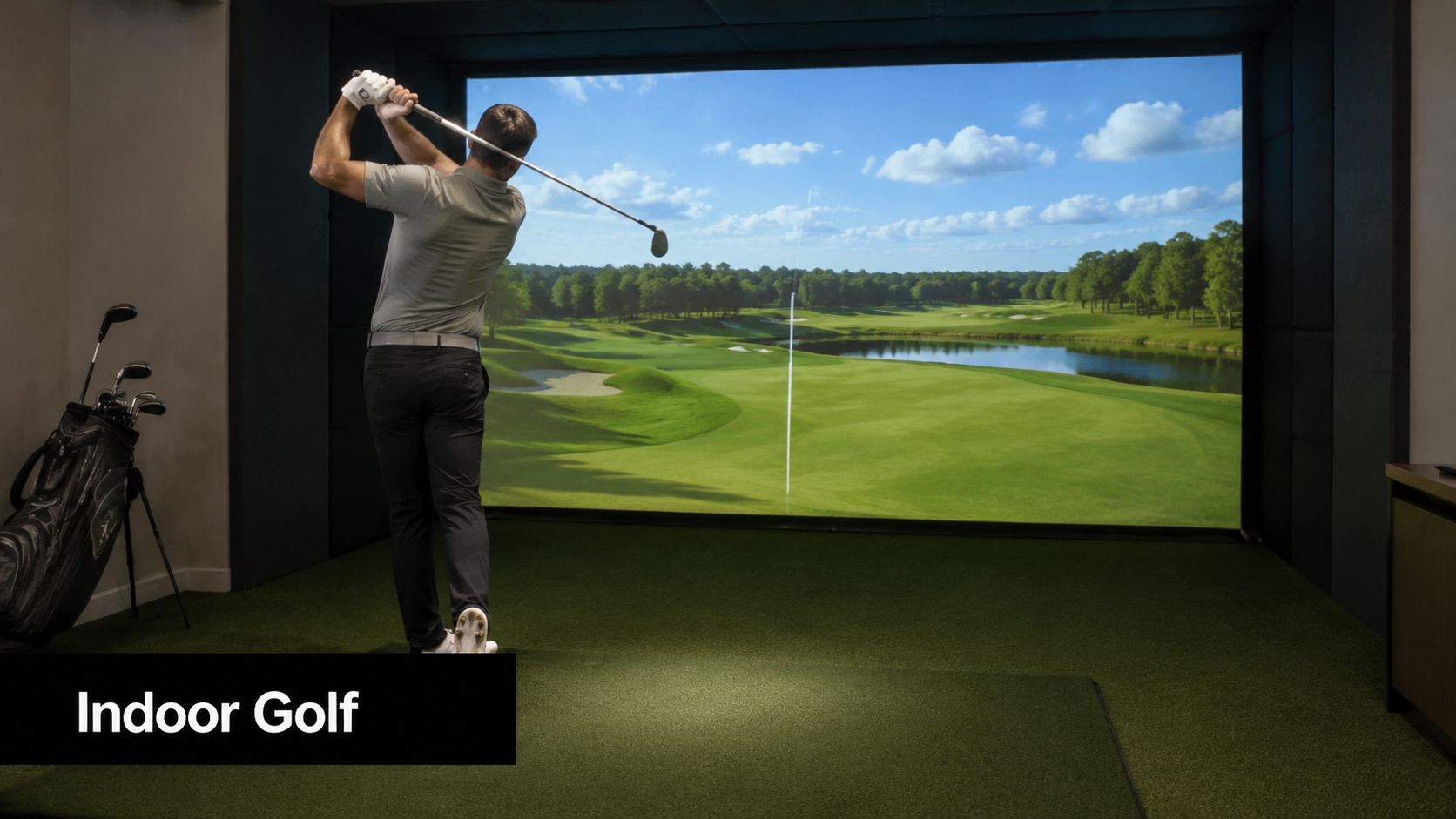 A man practicing his golf swing in a modern indoor golf simulator facility with a screen.
