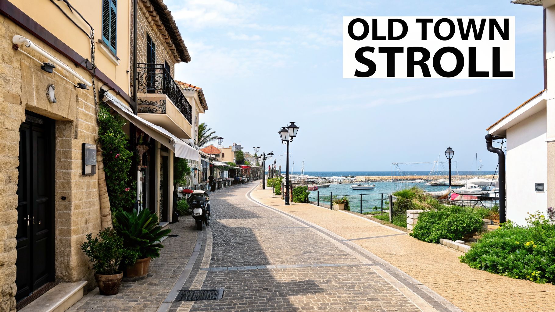 A picturesque old town street with traditional buildings, a cobbled path, and a view of boats in a sunny marina.