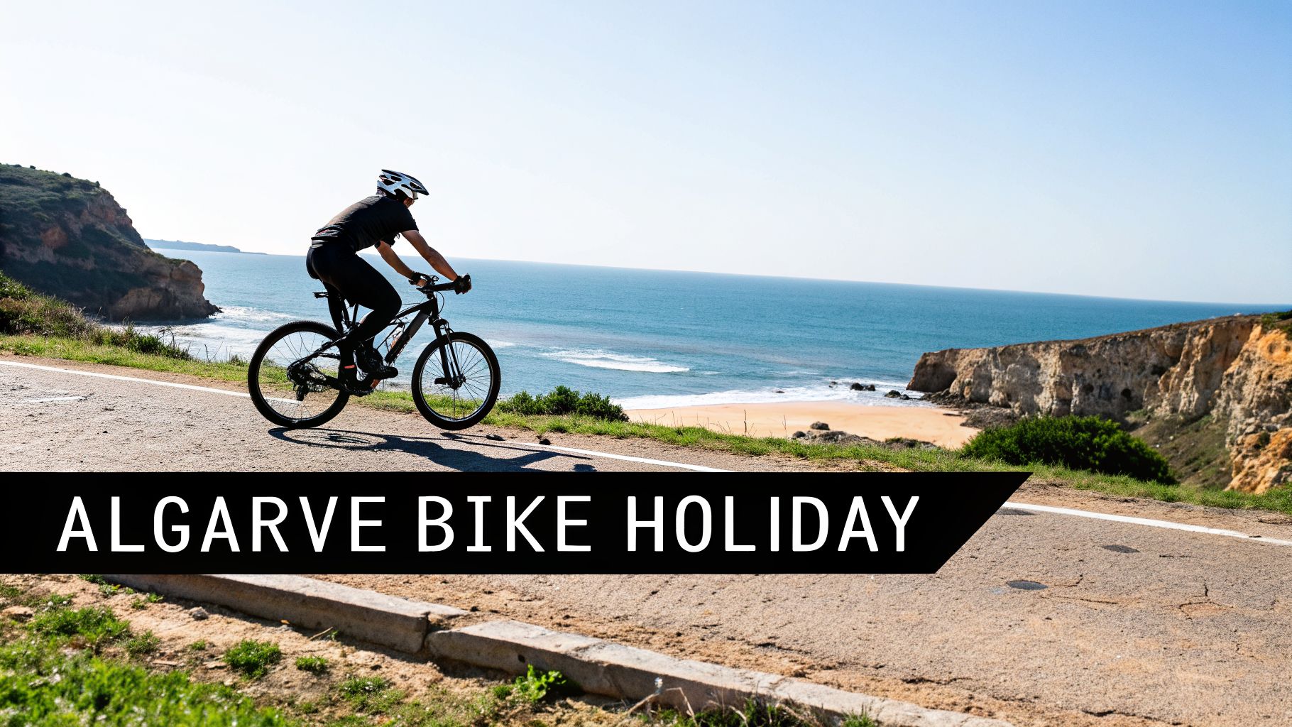 A person cycling on a coastal road overlooking a sandy beach and cliffs under a clear sky.