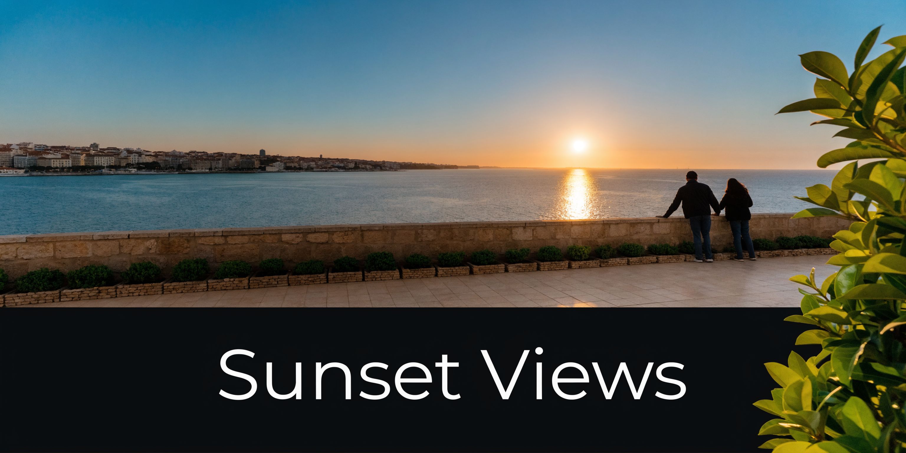 A couple looks out over the ocean at a beautiful sunset in Lisbon, Portugal.