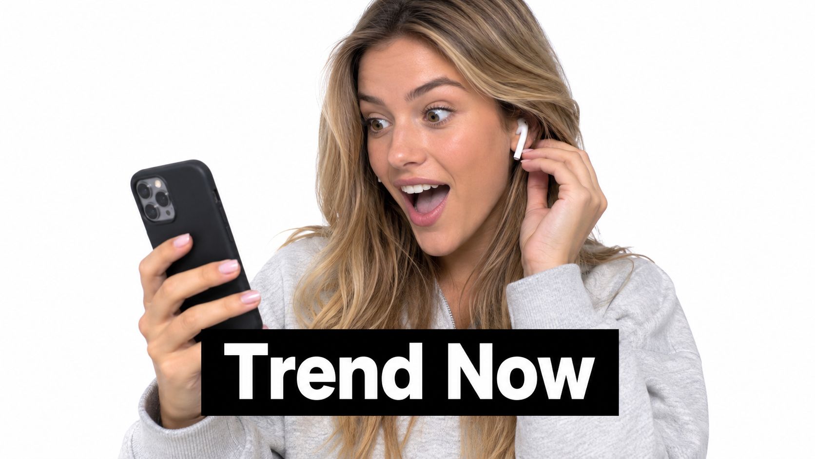 A woman looks surprised while holding a smartphone and touching her white wireless earbud against a white background.