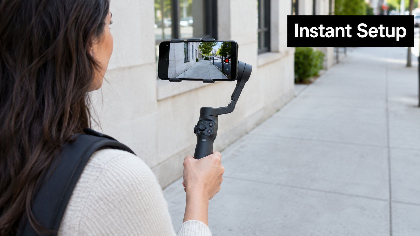 A woman holding a smartphone mounted on a DJI gimbal stabilizer outdoors on a city sidewalk.
