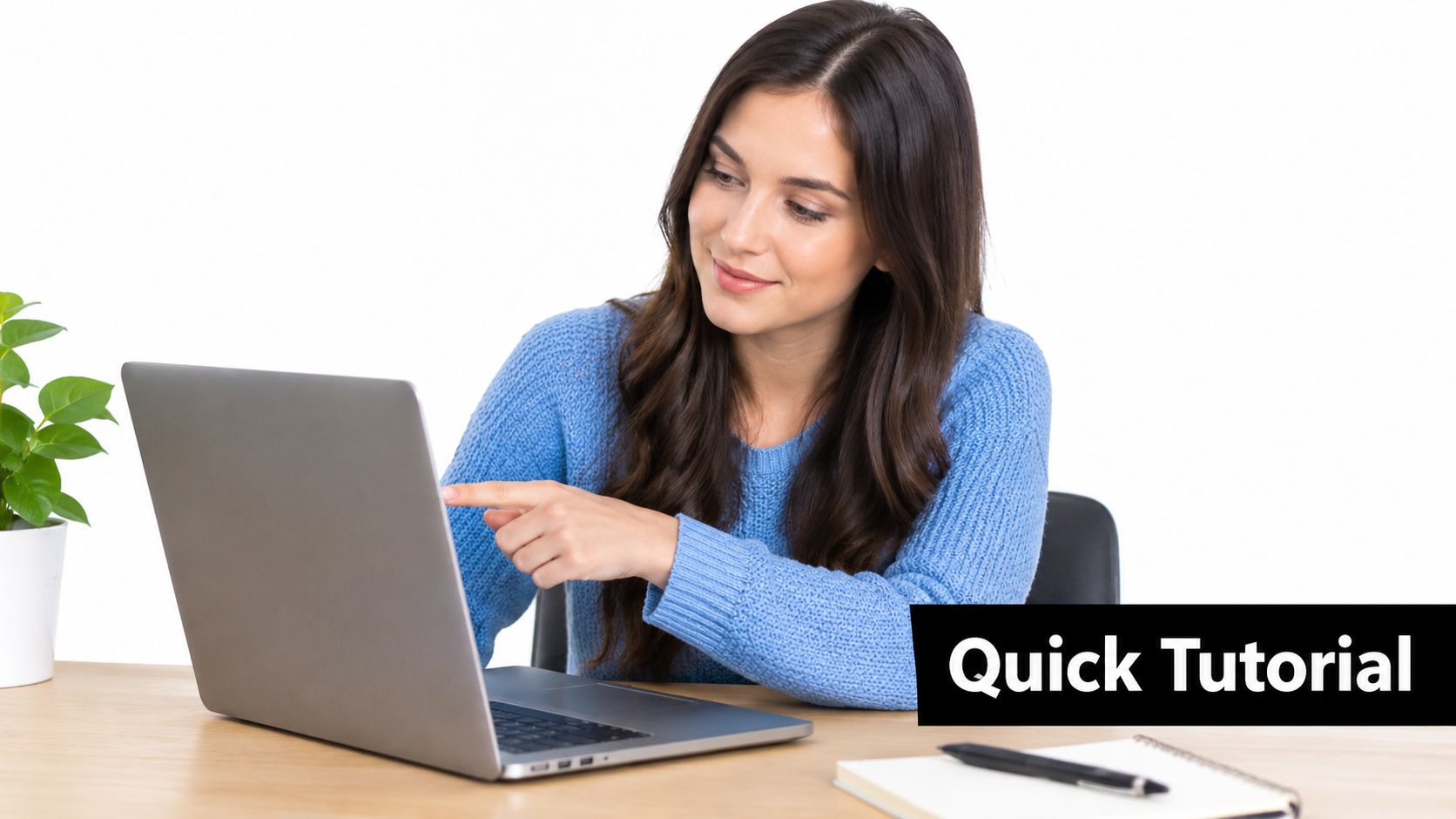 A smiling woman in a blue sweater points at her laptop screen for a quick tutorial.