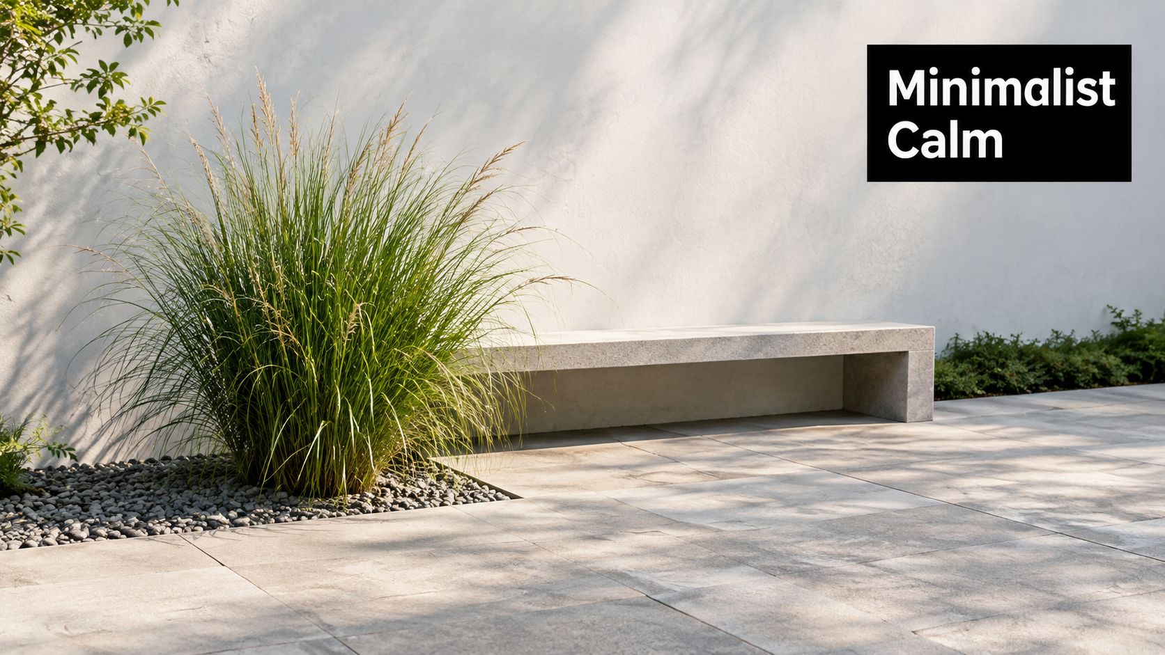 A modern stone bench sits on a minimalist patio next to tall ornamental grasses and white walls.