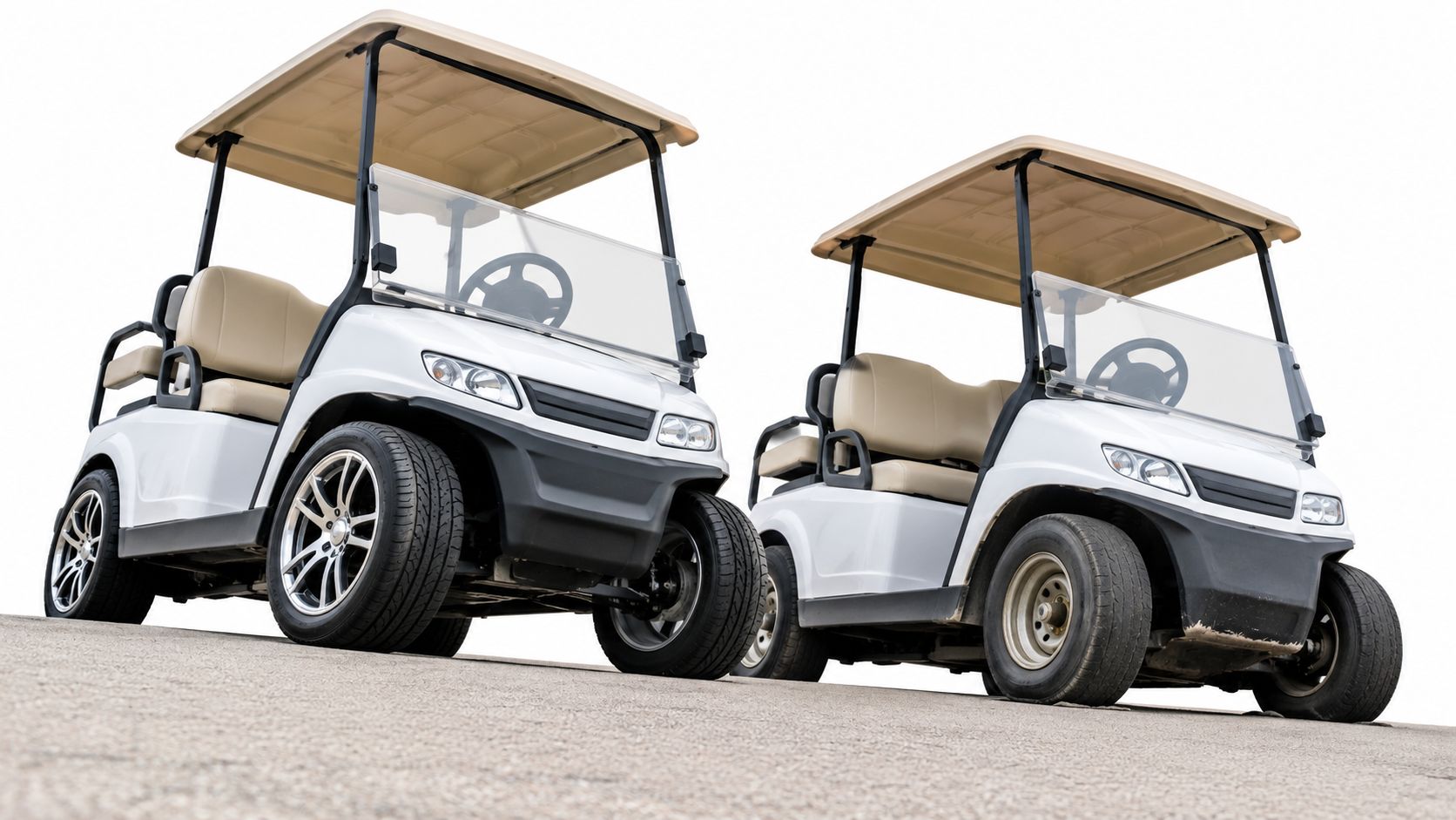 Two modern white golf carts with beige seats parked side-by-side on an asphalt surface.