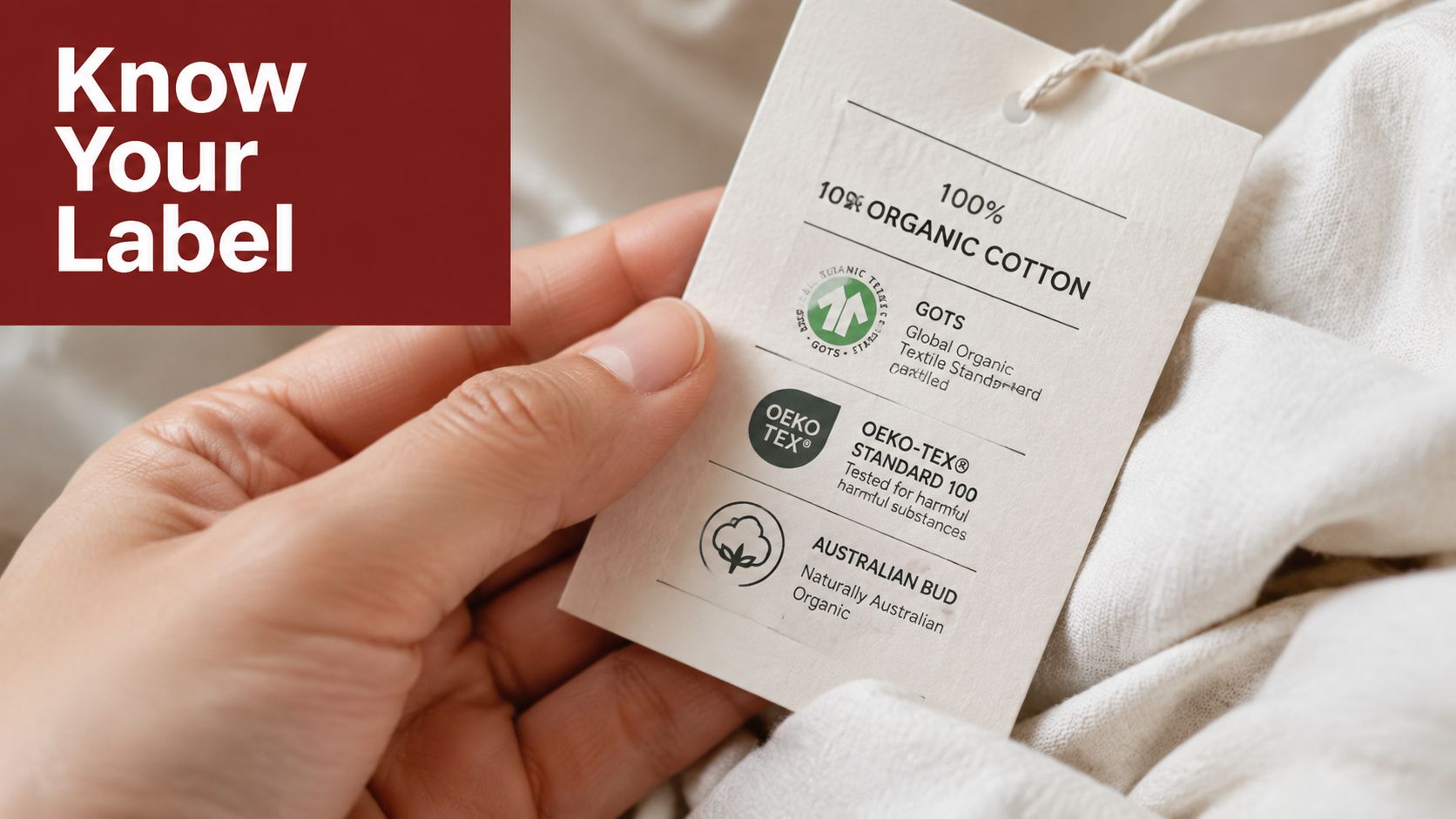 A hand holding a clothing tag featuring certifications for organic cotton and sustainable fabric quality standards.