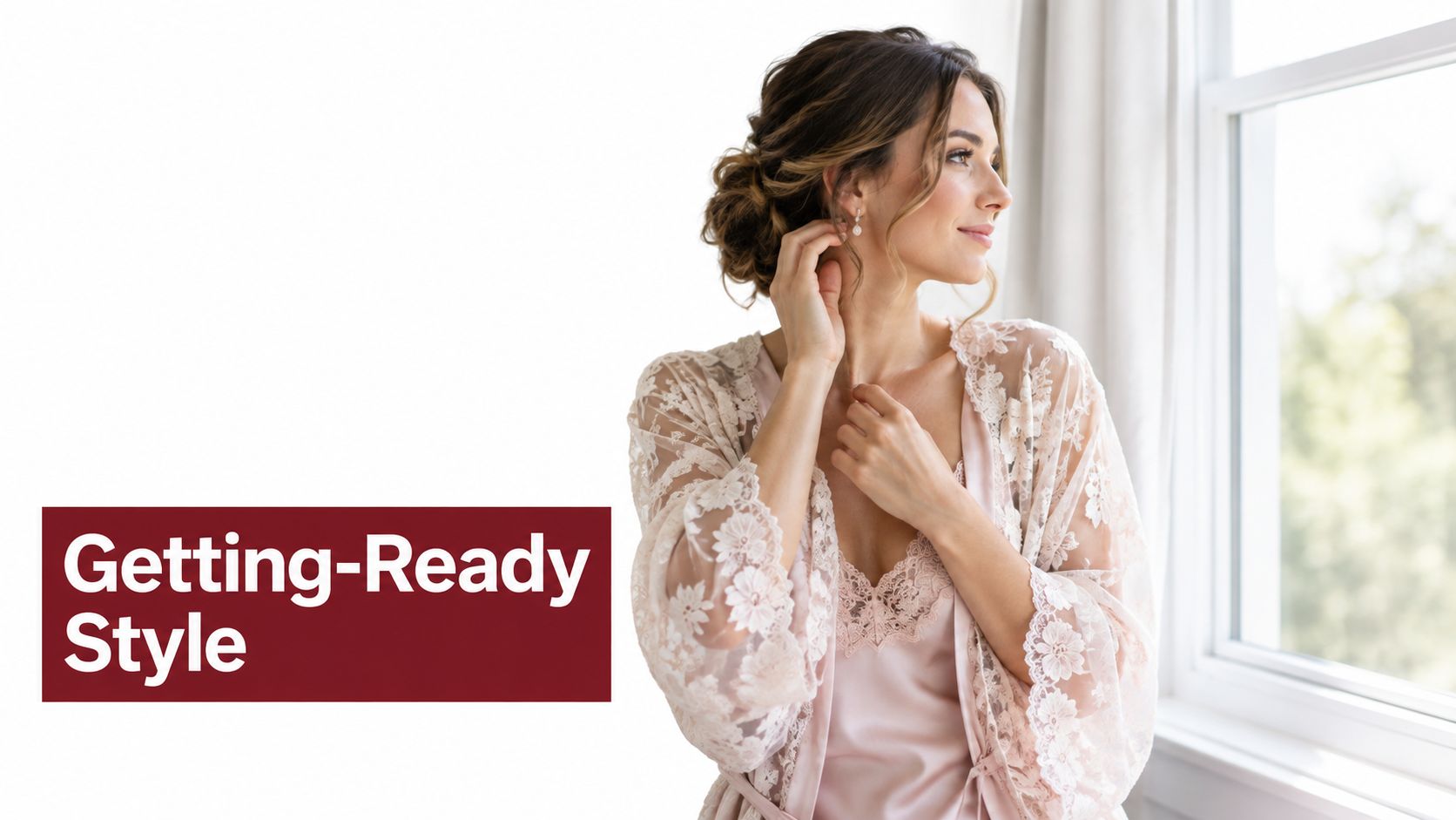 A beautiful bride in a delicate floral lace robe looking out the window while getting ready.