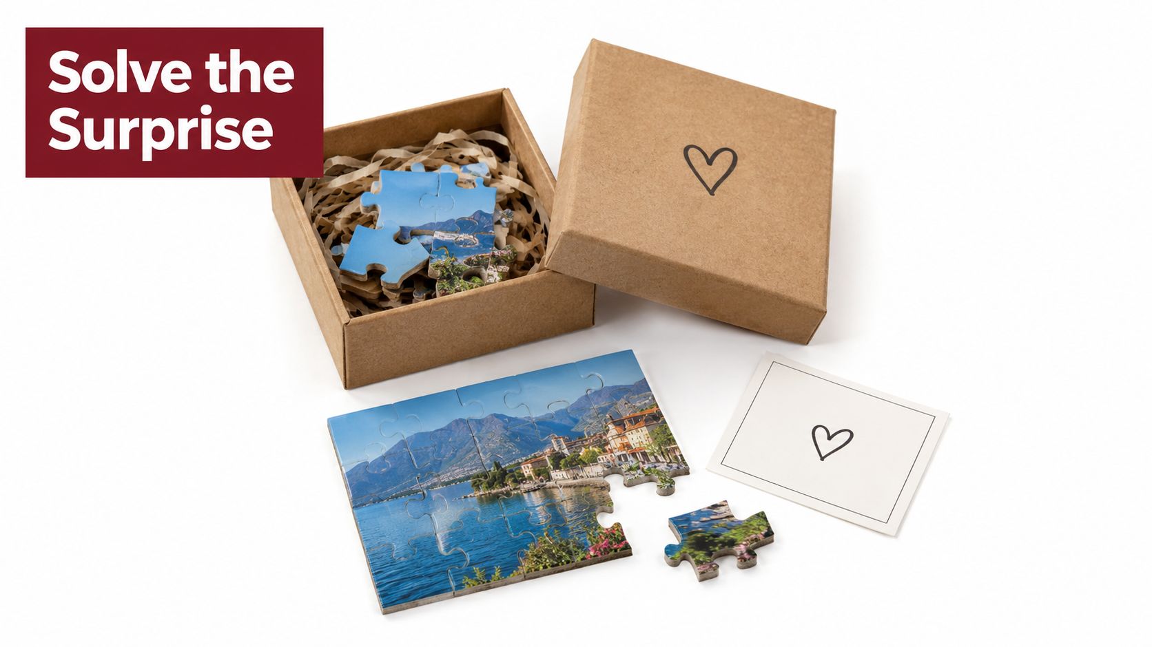 A small cardboard gift box containing puzzle pieces alongside an assembled landscape puzzle and a card with a heart.
