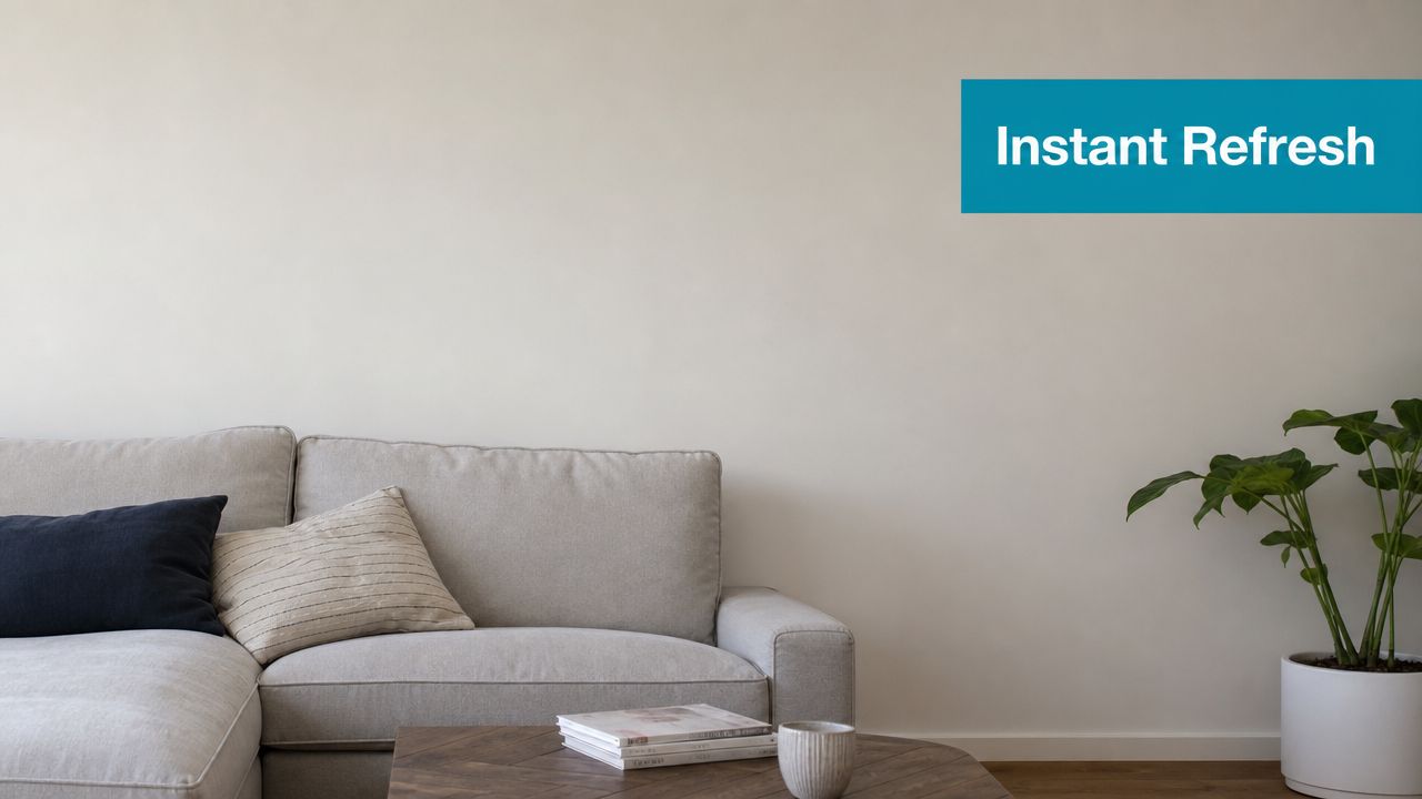 A modern, minimalist living room featuring a comfortable gray sofa, a wooden coffee table, and a green plant.