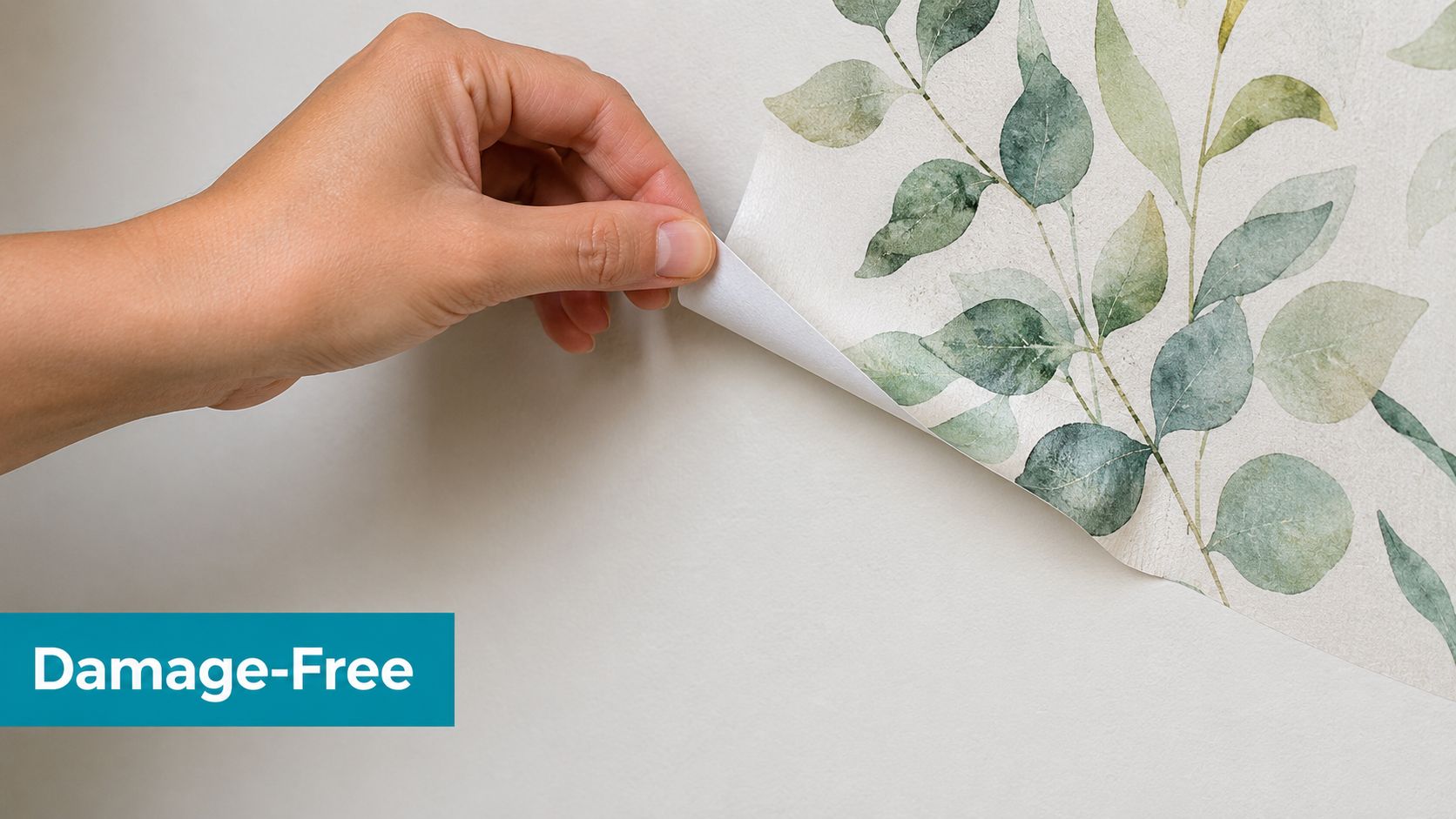 A hand peeling a floral patterned, self-adhesive wall decal off a clean, smooth white wall.