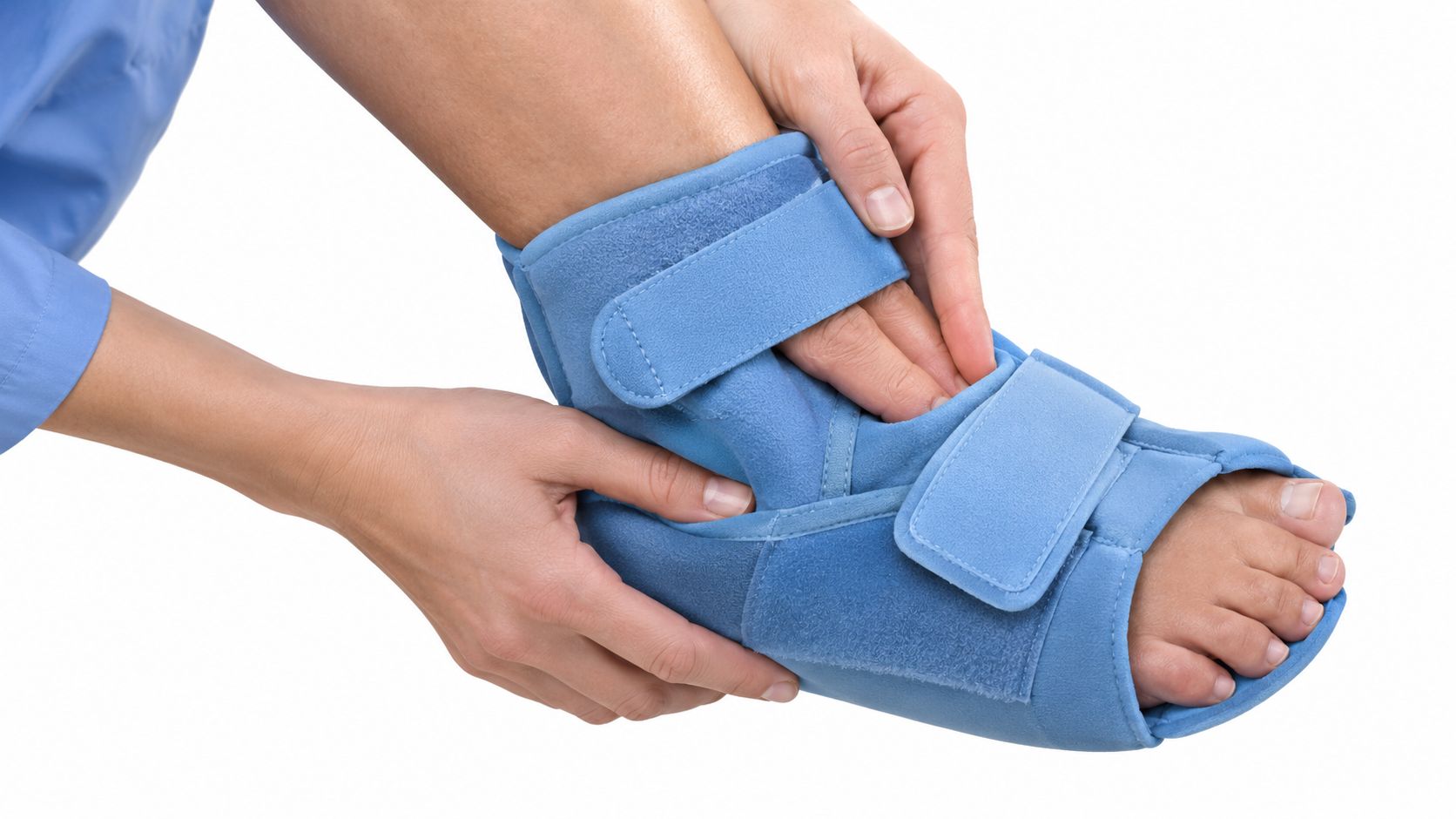 A person using their hands to adjust a blue medical boot on their injured foot.