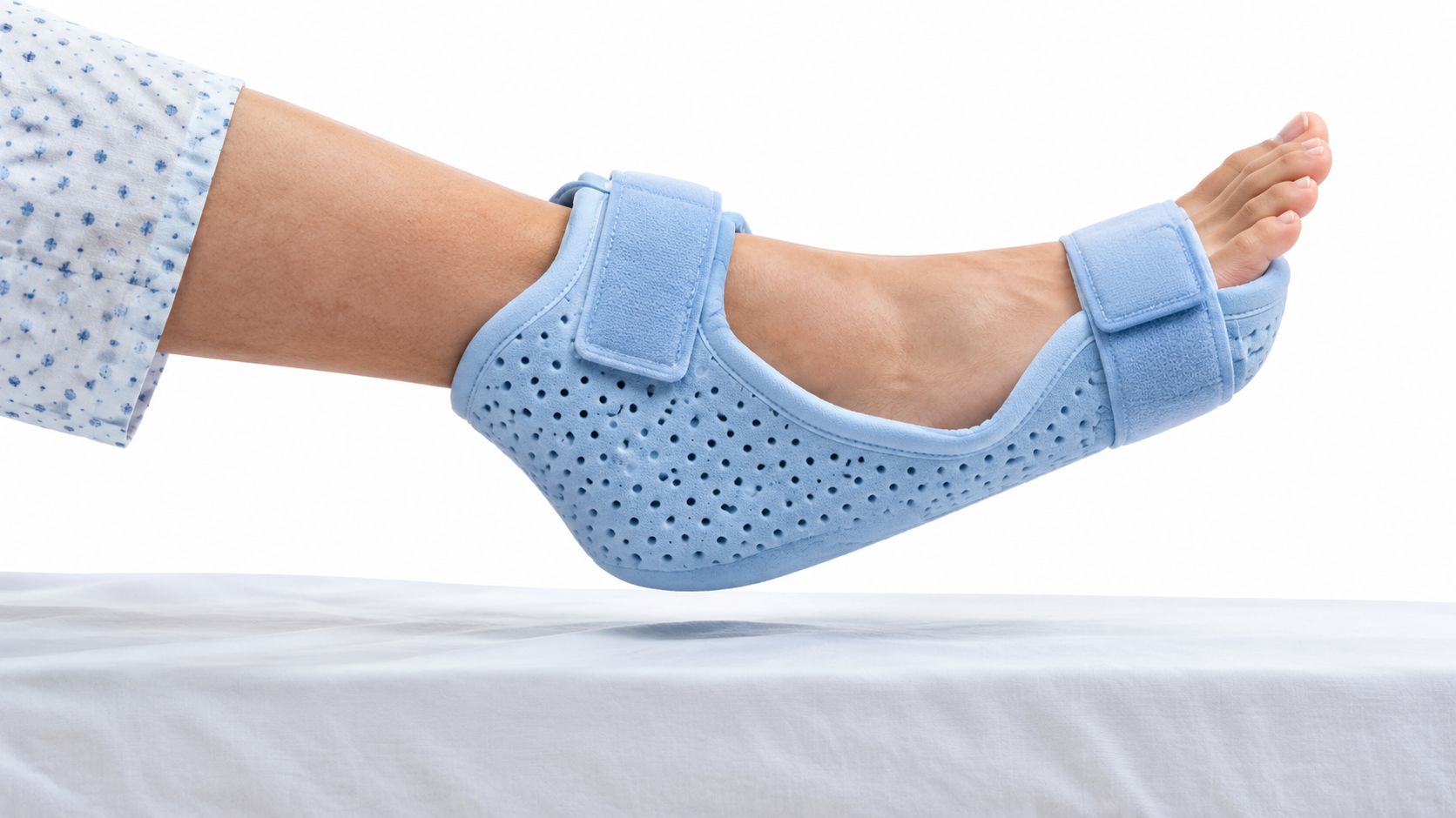 A person wearing a light blue orthopedic heel protector boot on their foot while resting on a bed.