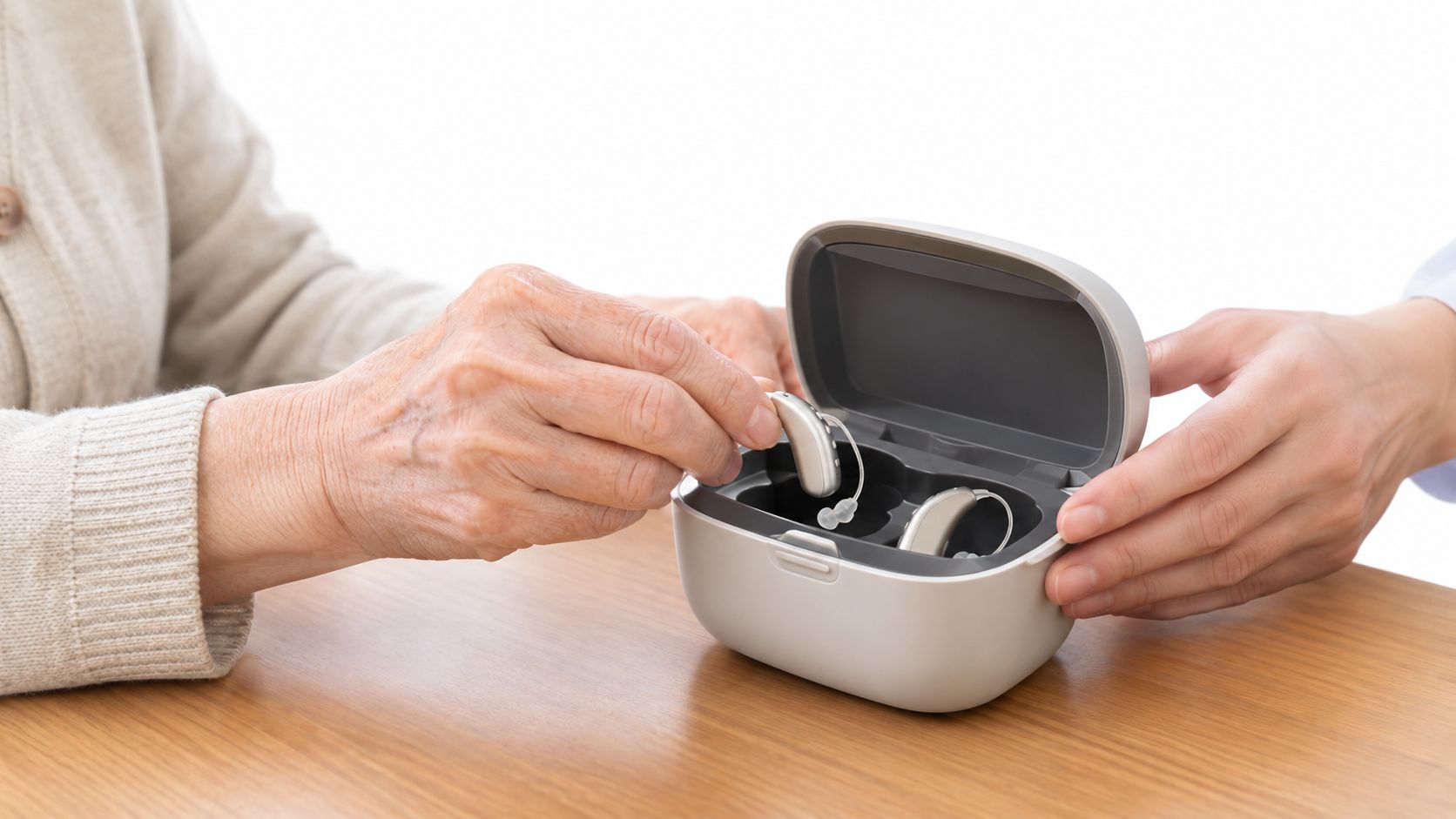 An elderly person is carefully placing a hearing aid into its portable charging and storage case.