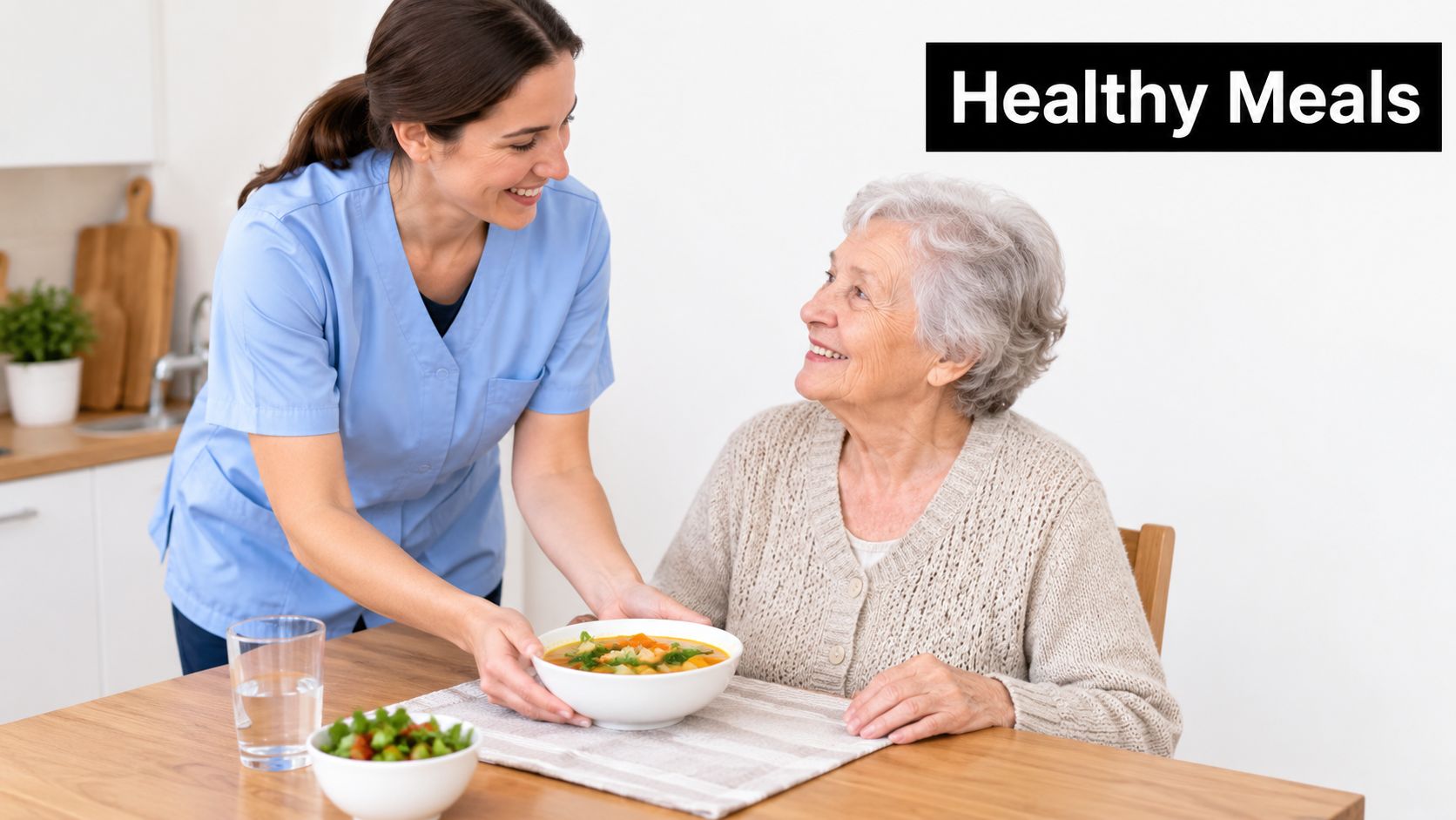 A smiling care worker in blue scrubs serving a bowl of healthy soup to an elderly woman.