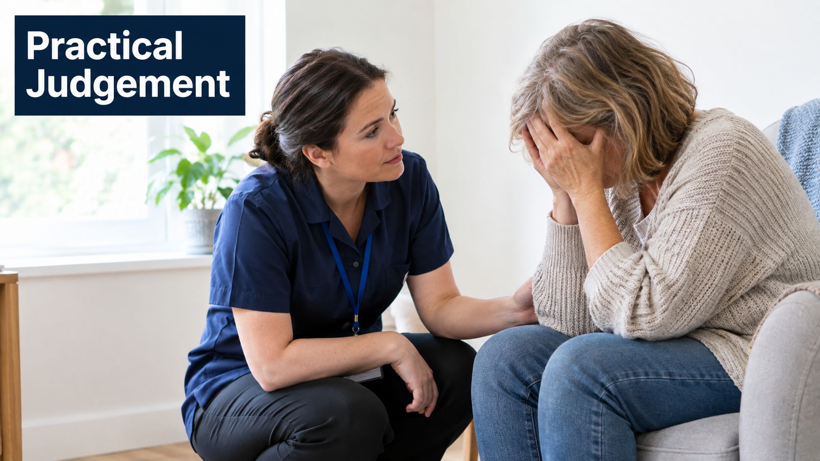 A female healthcare professional kneeling and comforting an emotional older woman sitting in a chair.