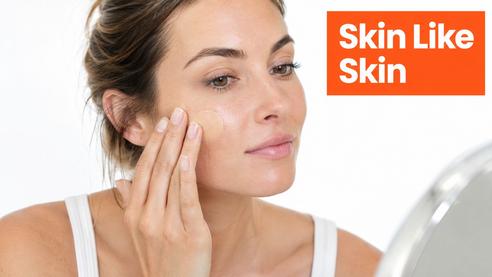 A woman applying natural foundation to her cheek in front of a mirror for a fresh look.