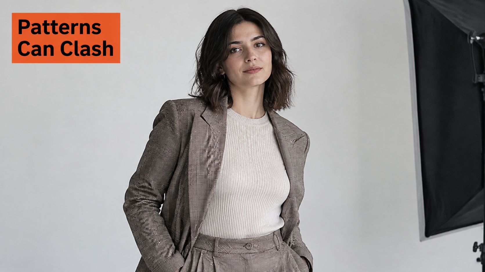 A professional woman wearing a stylish plaid suit blazer standing in a bright photo studio setting.