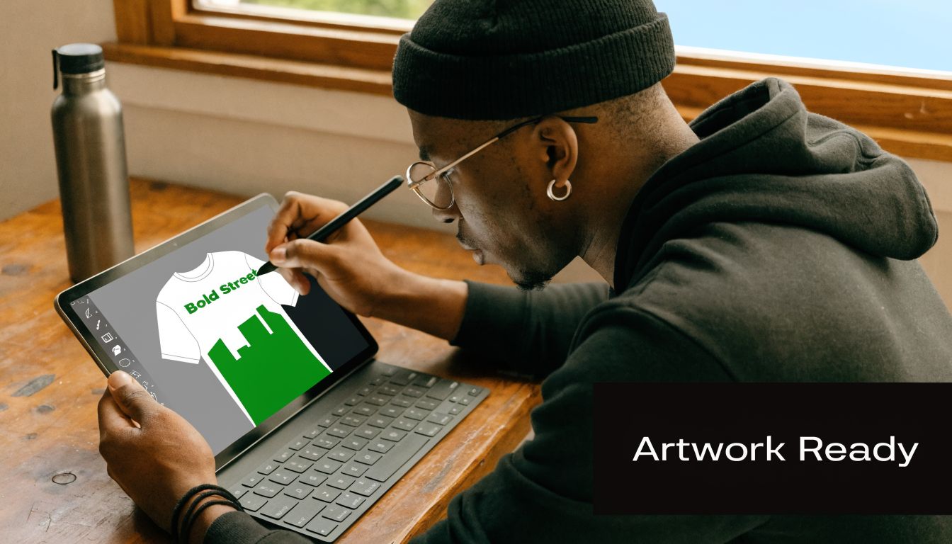 A creative designer using a stylus on a tablet to create custom t-shirt artwork.