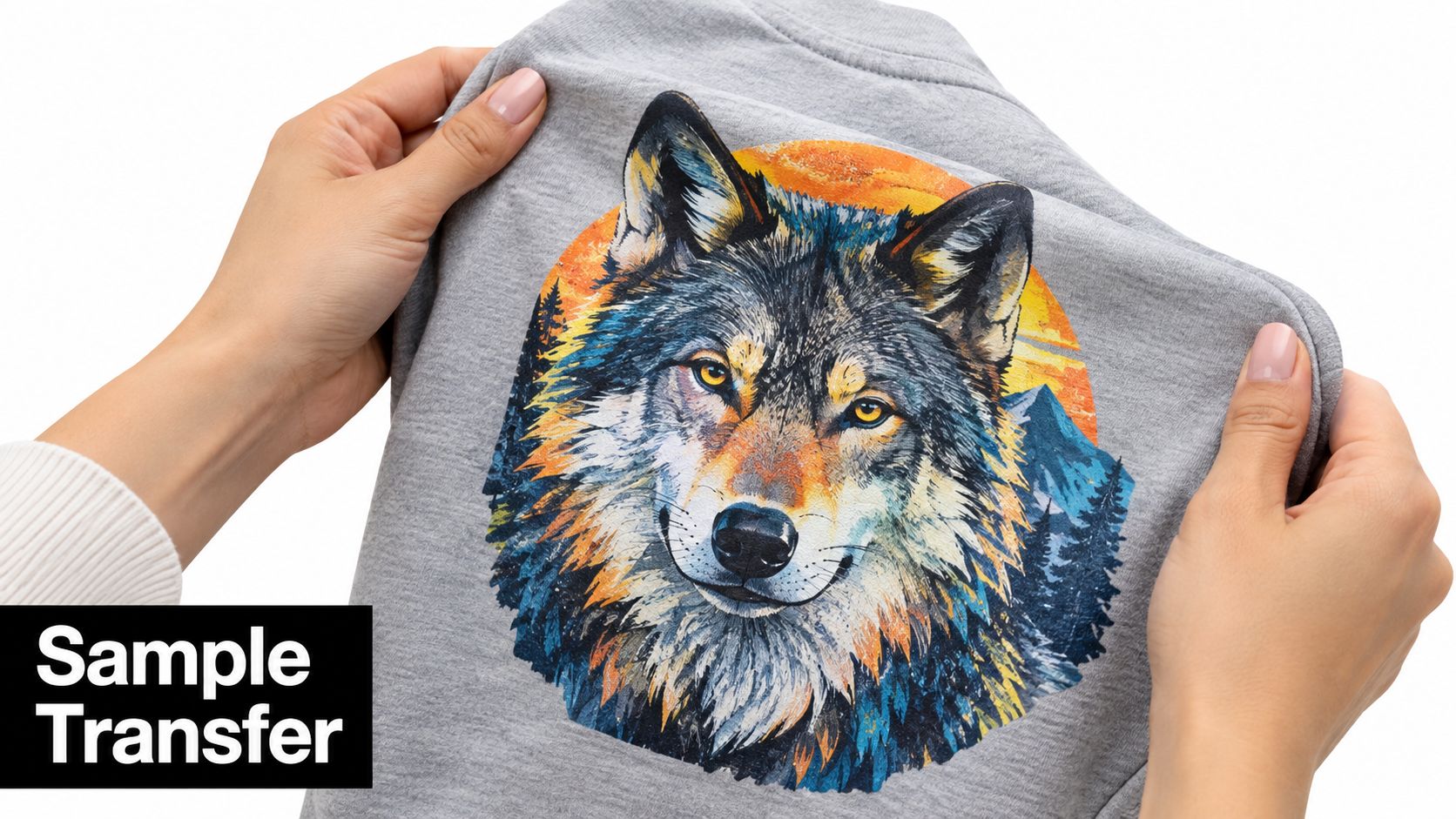 A close-up of hands holding a grey t-shirt featuring a colorful artistic wolf graphic design transfer.