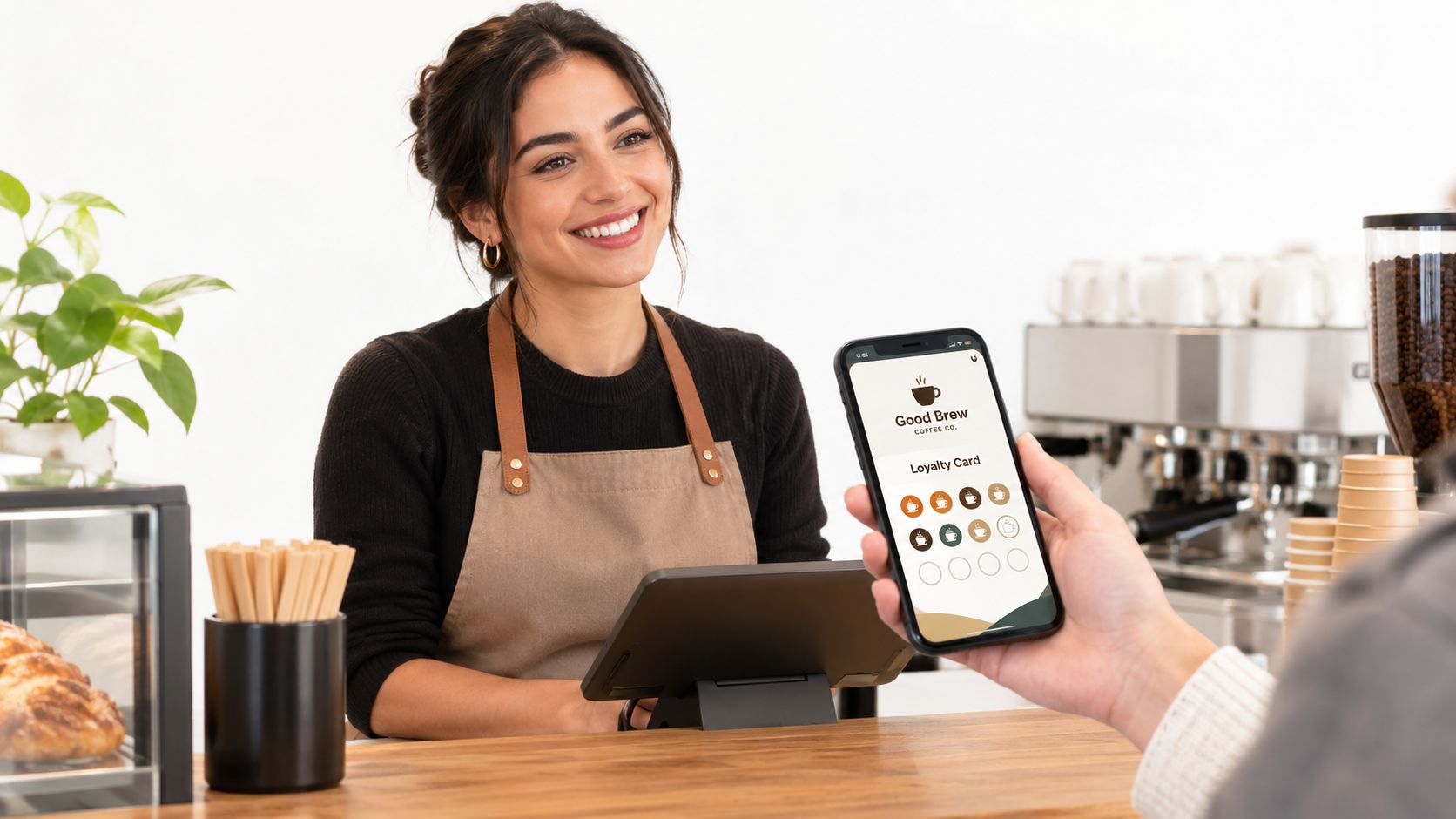 A friendly barista smiles while a customer presents a digital loyalty card on their smartphone for scanning.