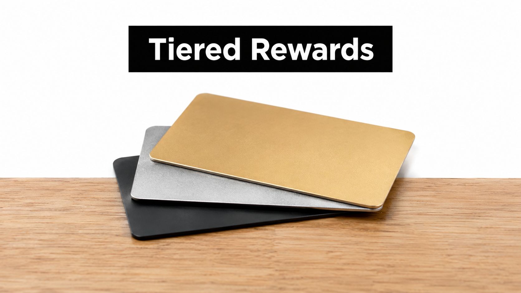 A stack of three tiered reward cards in gold, silver, and black resting on a wooden surface.