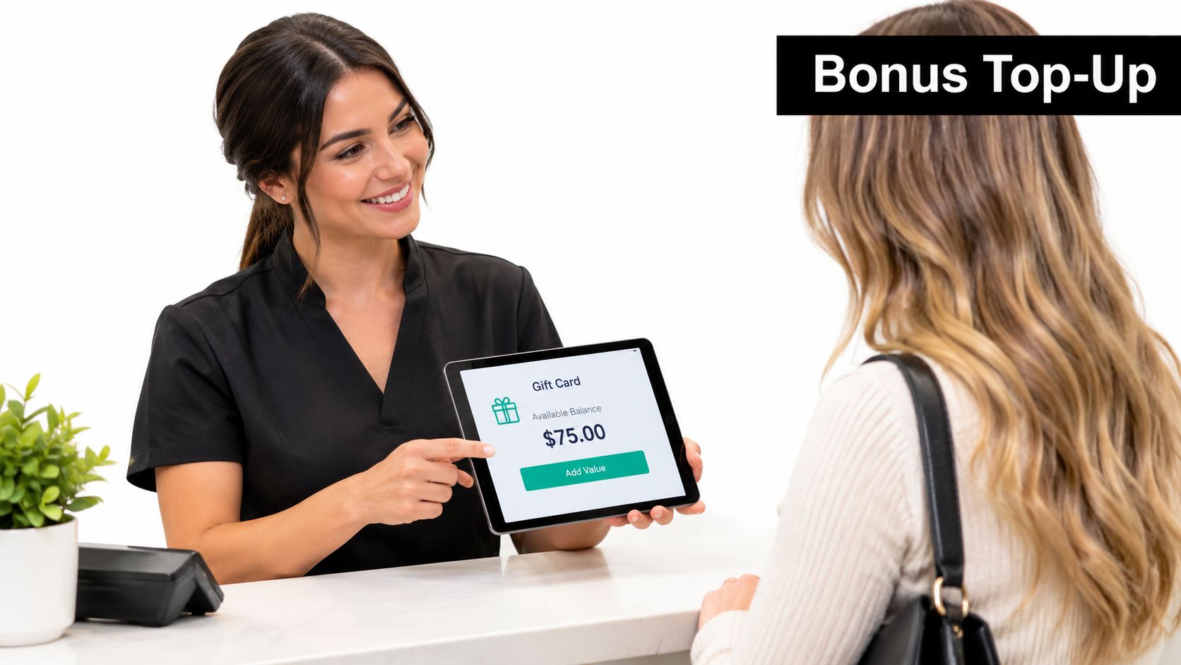 A friendly receptionist presenting a tablet displaying a seventy-five dollar gift card balance to a customer.