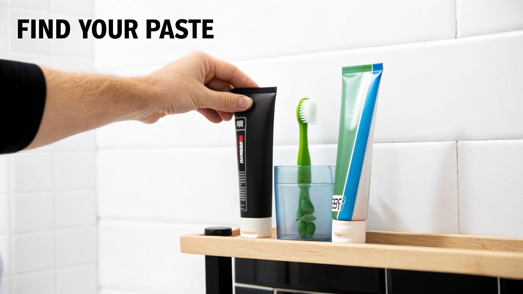 A hand reaches for a black tube of toothpaste on a bathroom shelf, next to a toothbrush.