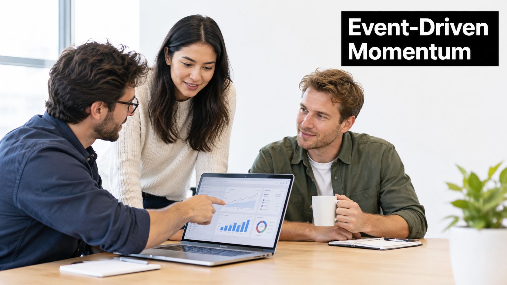 A diverse team of three colleagues collaborate in an office while reviewing analytics on a laptop screen.