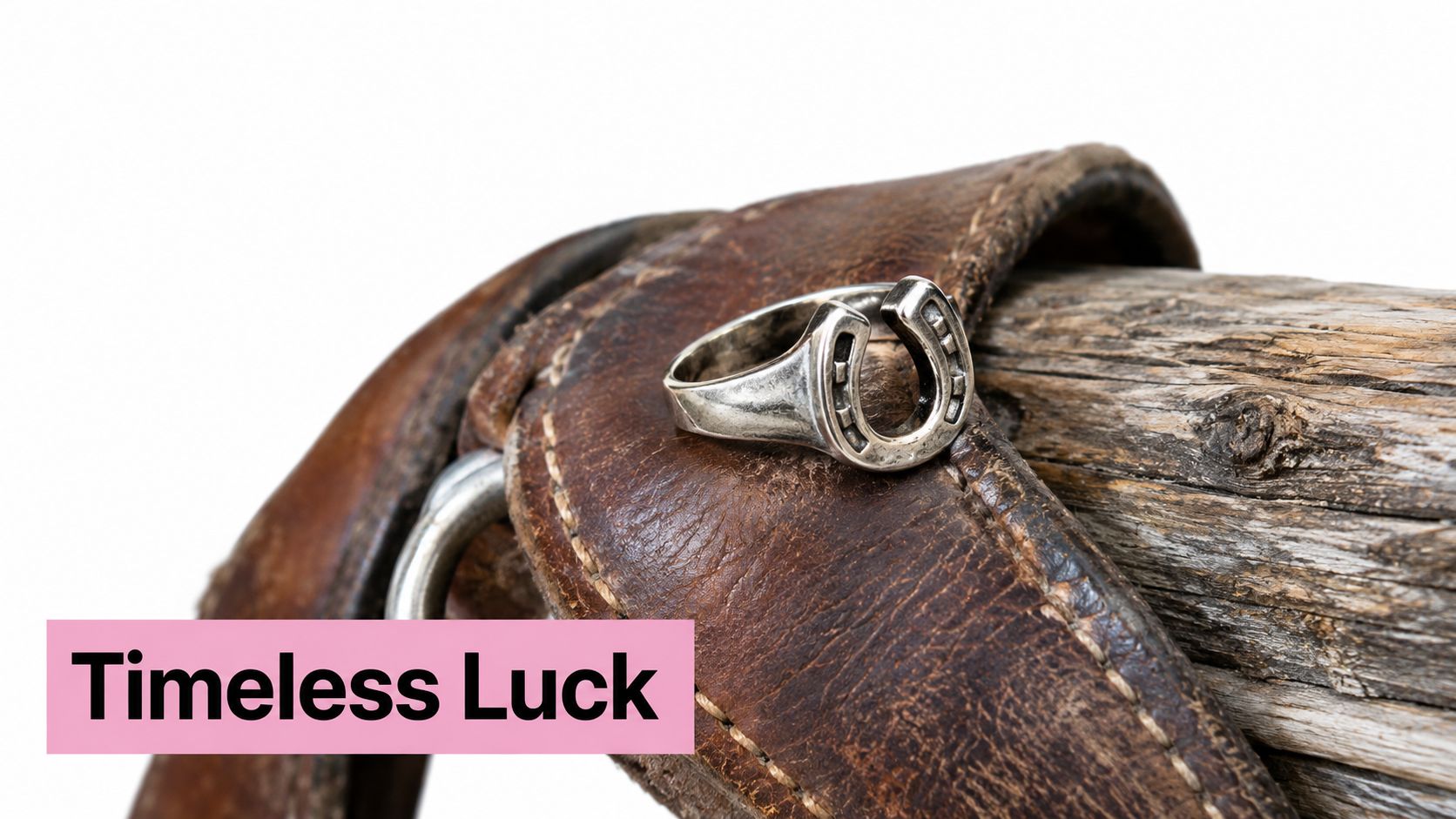 A silver horseshoe ring resting on a worn leather saddle strap next to a rustic wooden post.