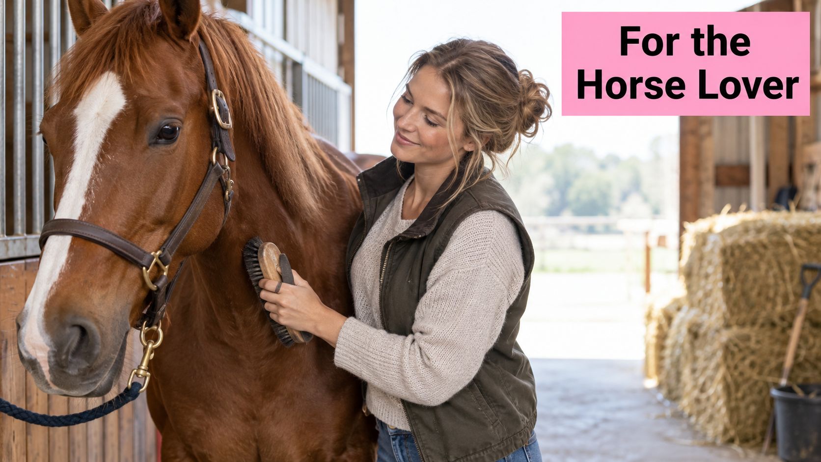A woman smiling while grooming a brown horse inside a stable, perfect for a horse owner gift.