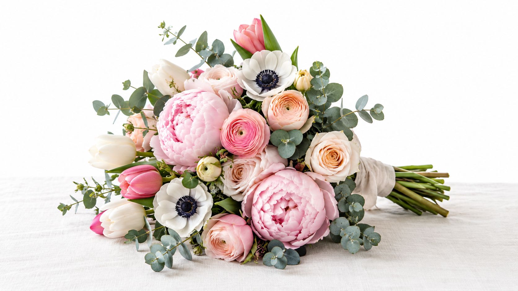 En smuk buket med lyserøde pæoner, hvide anemoner og friske blomster, perfekt som gave til Mors Dag.