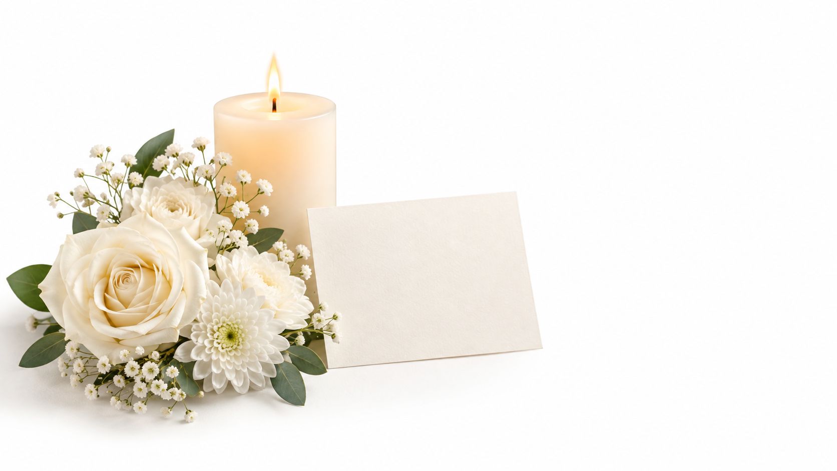 Et smukt hvidt kort placeret ved siden af et tændt stearinlys og en buket af hvide roser og blomster.
